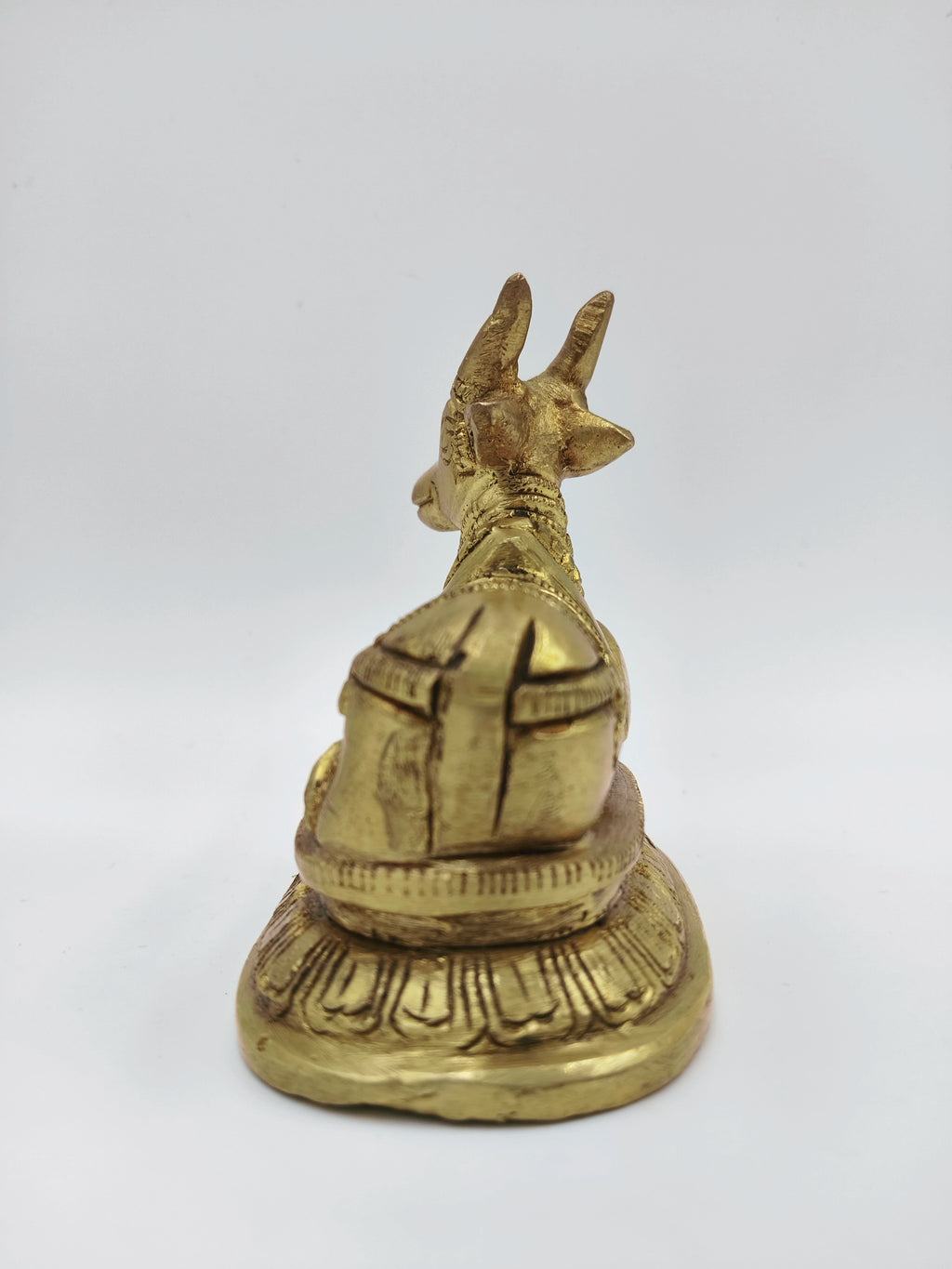 Small brass Nandi figurine sitting on decorated base, rear view