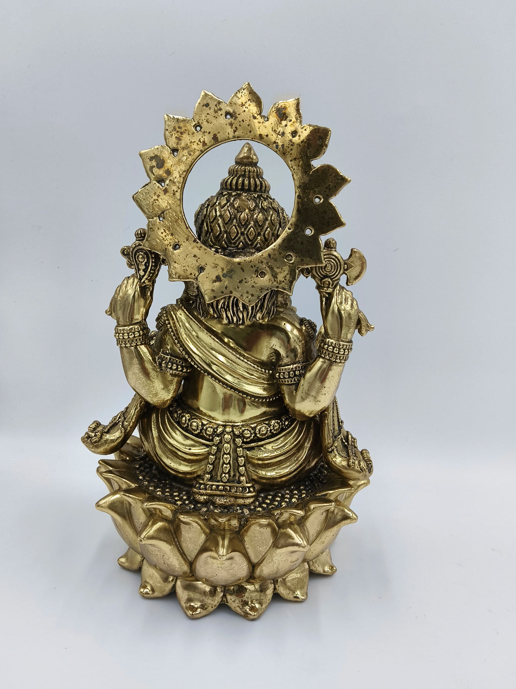 Back view of large brass Ganesh statue seated on lotus pedestal