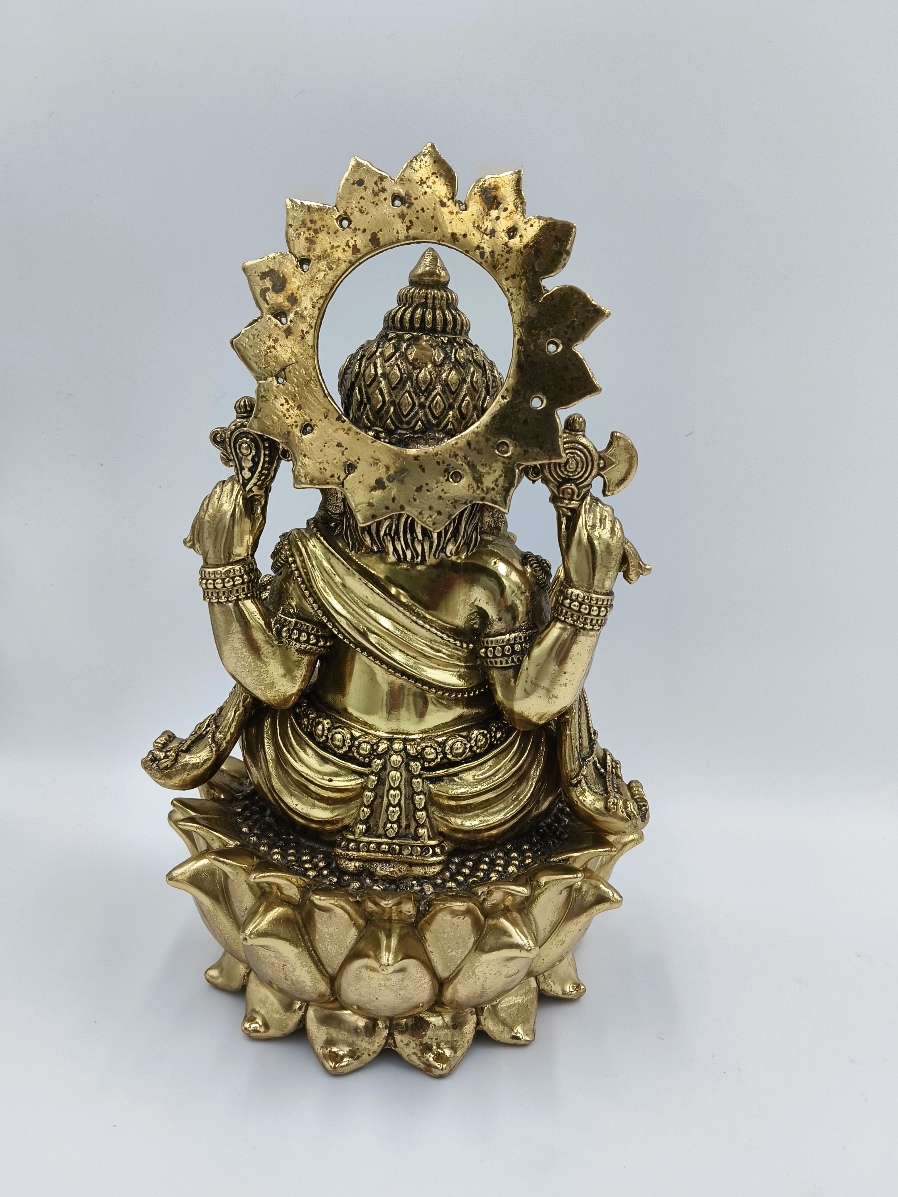 Back view of large brass Ganesh statue seated on lotus pedestal