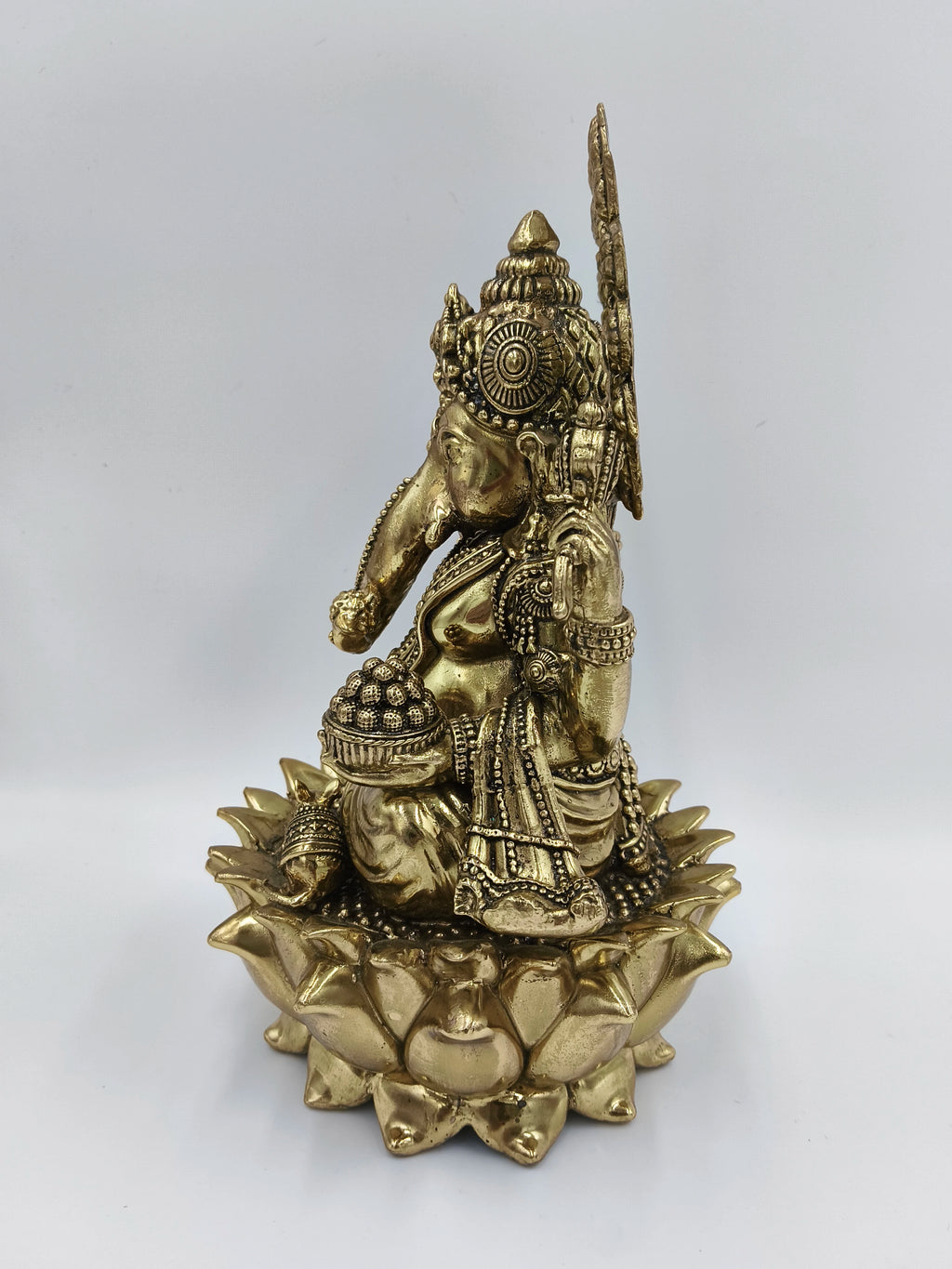 Side view of large brass Ganesh statue seated on a lotus base