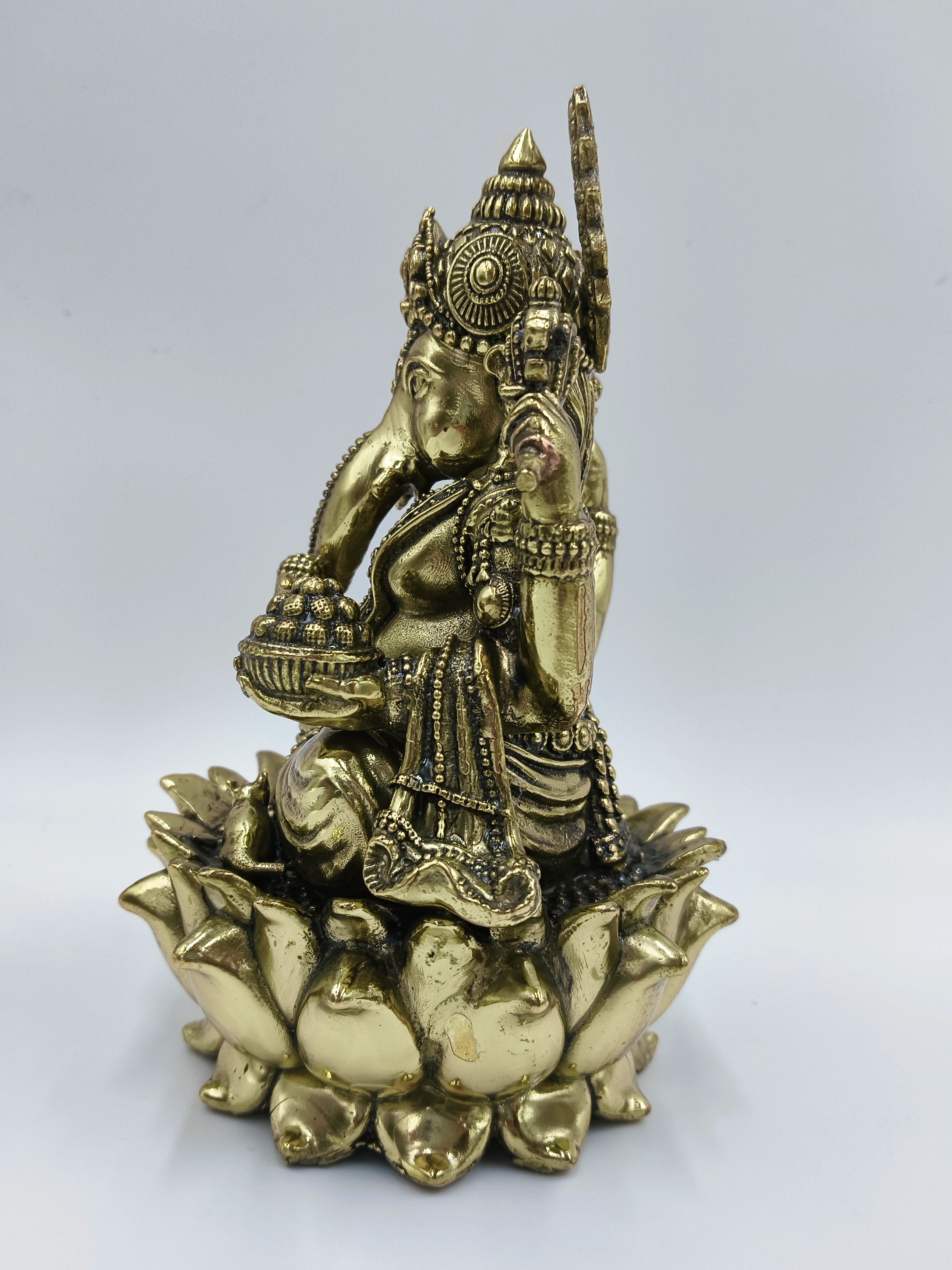 Brass sculpture of Lord Ganesh sitting on a lotus flower, side view