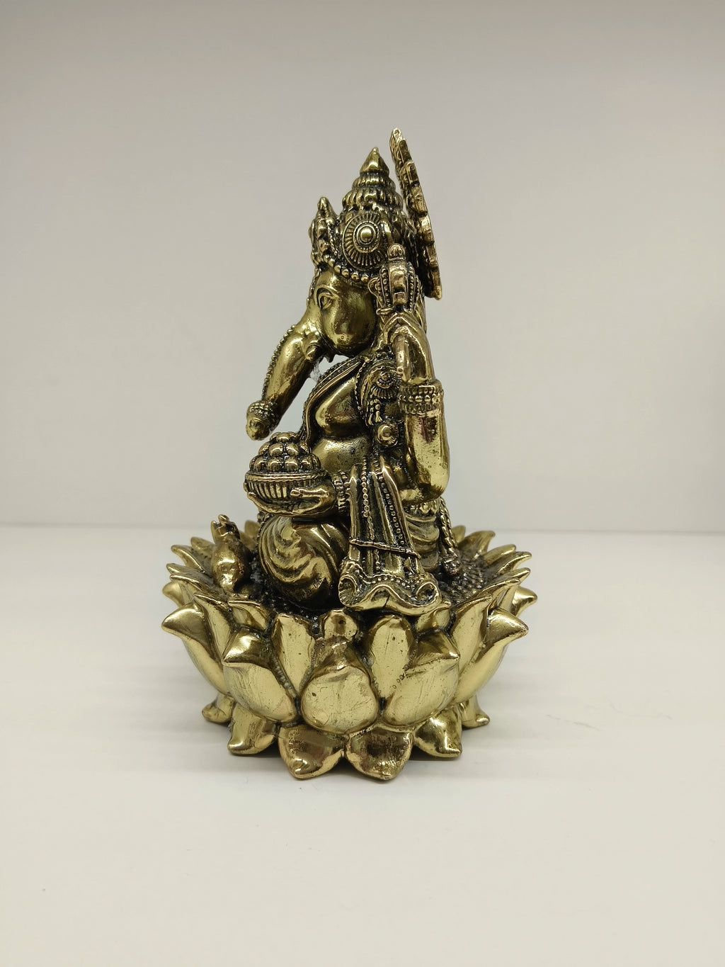 Side view of medium brass Ganesh statue seated on a lotus flower base