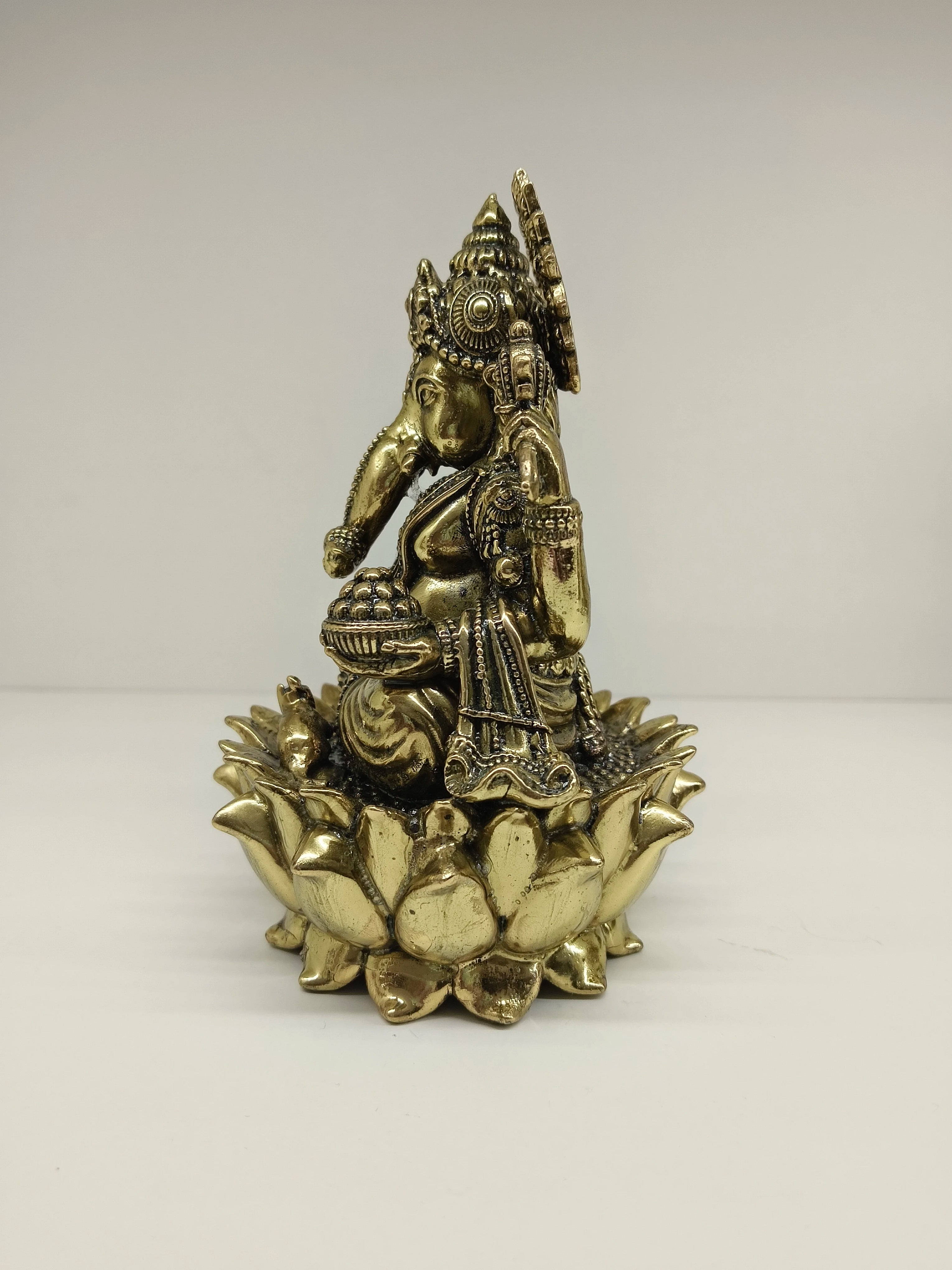 Side view of medium brass Ganesh statue seated on a lotus flower base