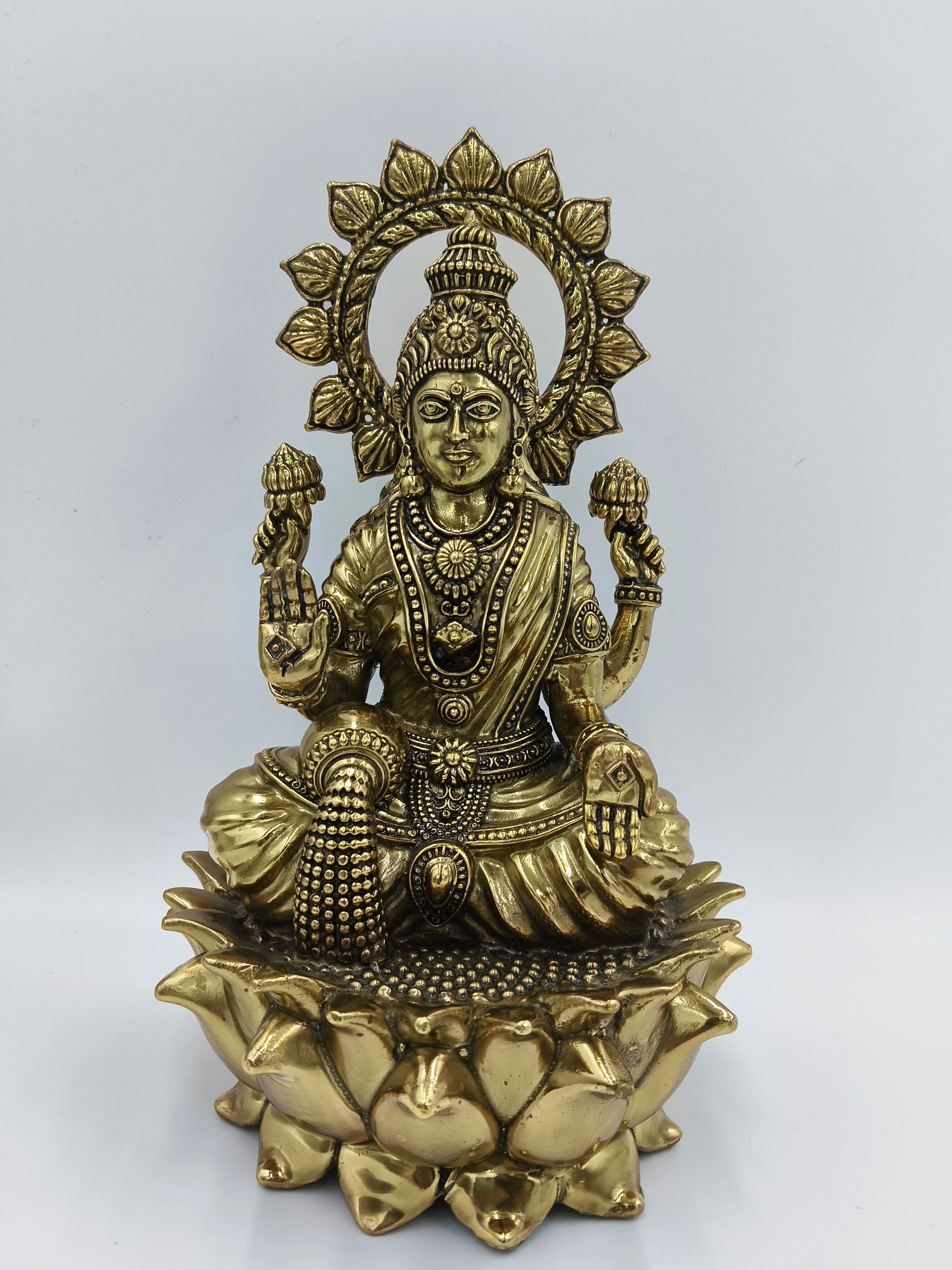 Large brass statue of Goddess Lakshmi seated on a lotus with decorative halo