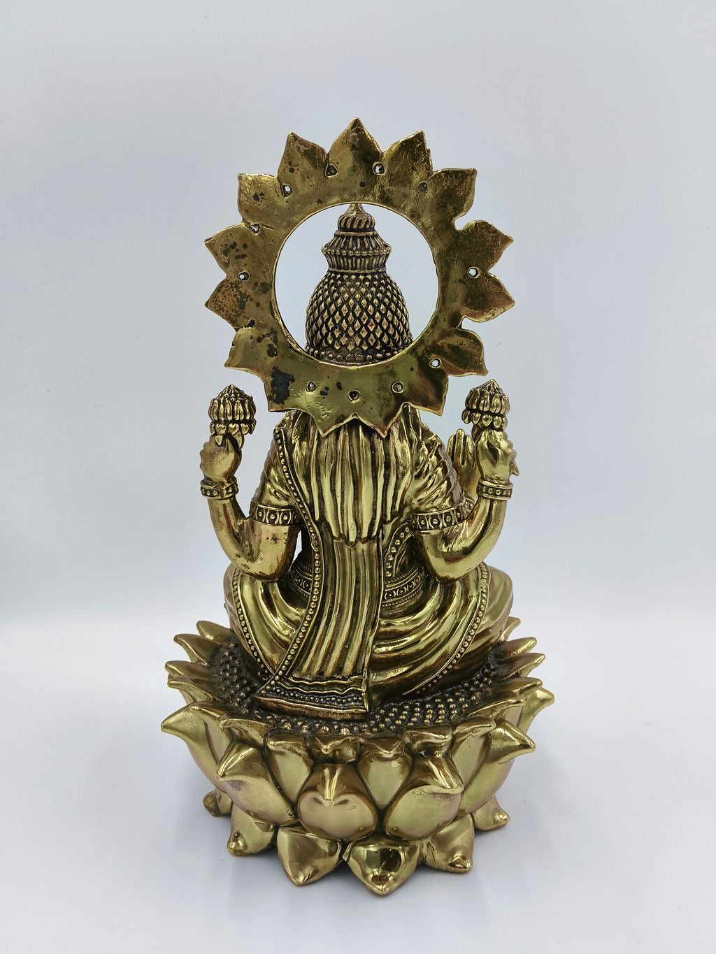 Back view of large brass statue of Goddess Lakshmi seated on a lotus flower