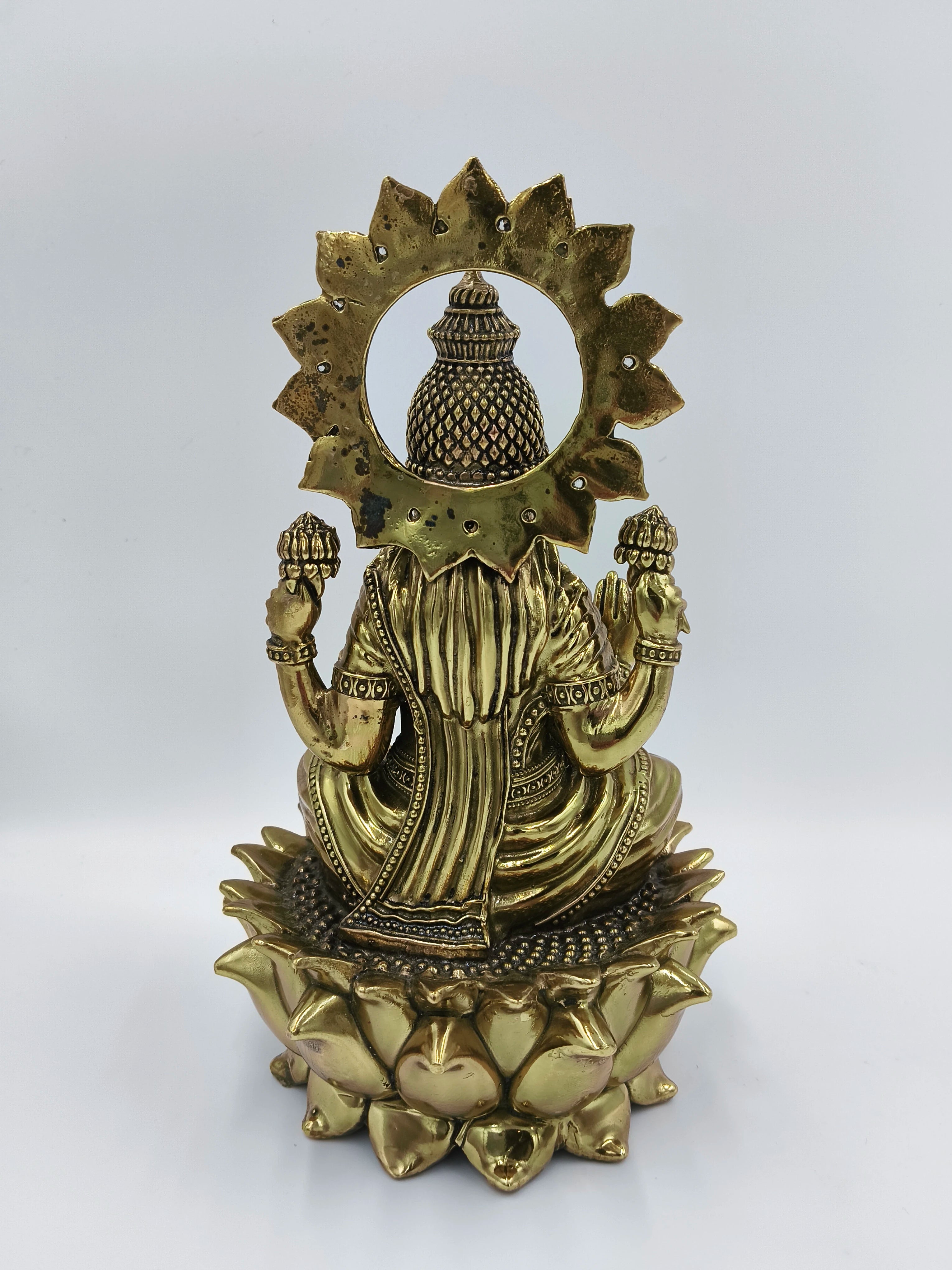 Back view of large brass statue of Goddess Lakshmi seated on a lotus flower