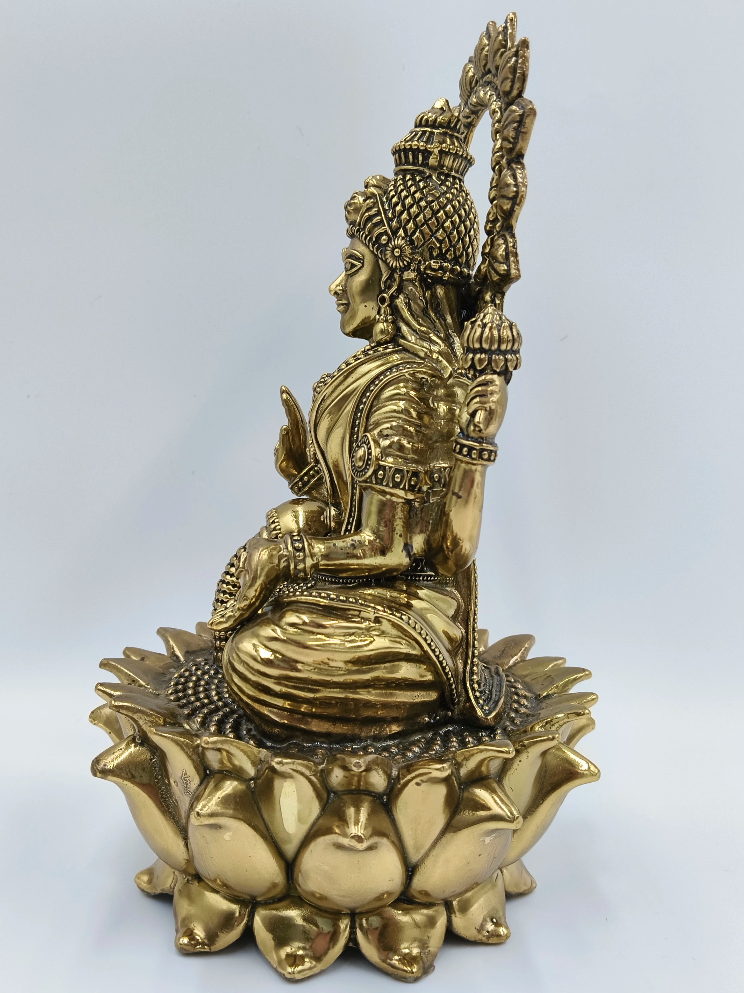 Side view of large brass statue of Goddess Lakshmi seated on lotus