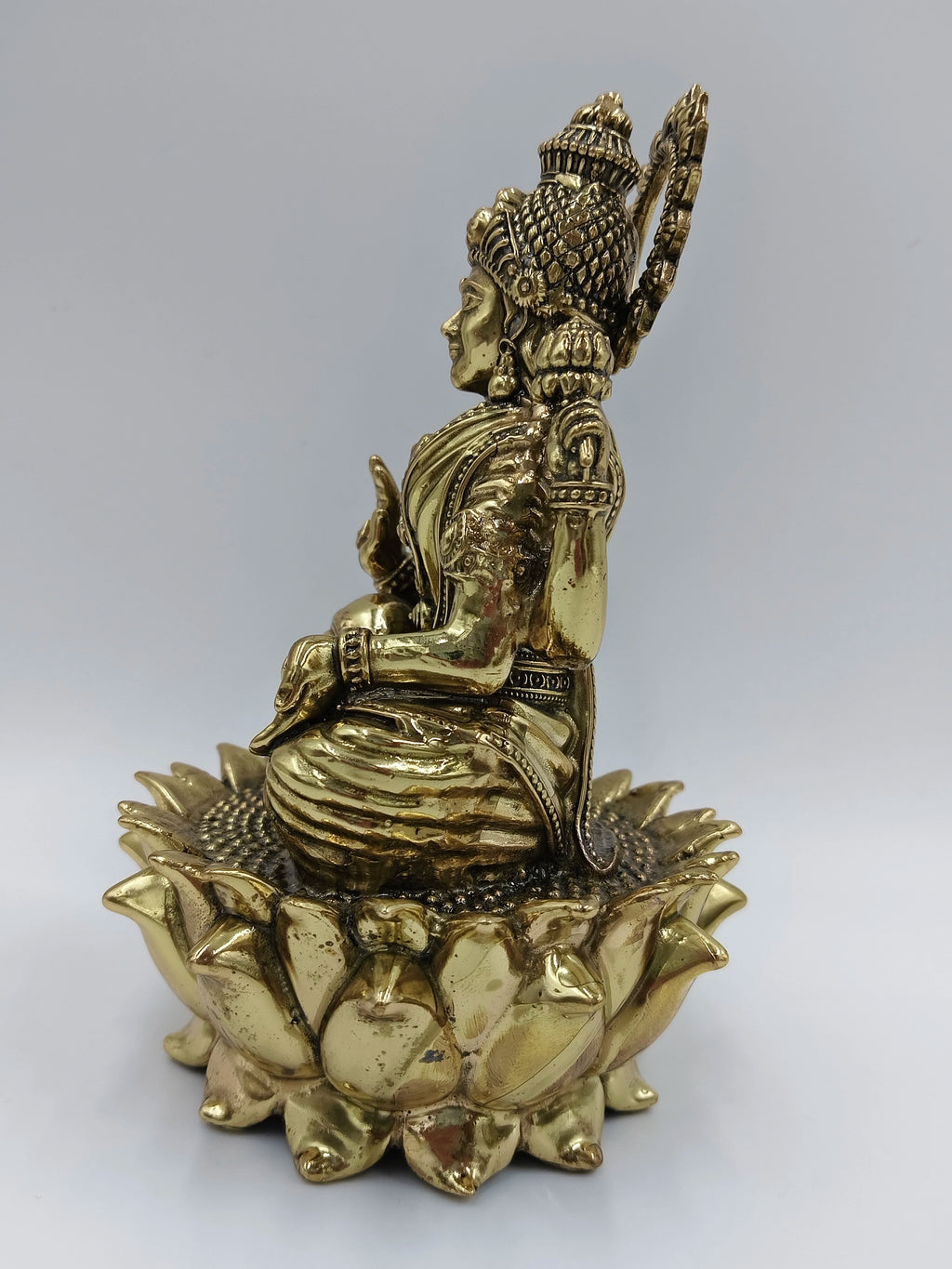 Side view of medium brass statue of Goddess Lakshmi sitting on lotus