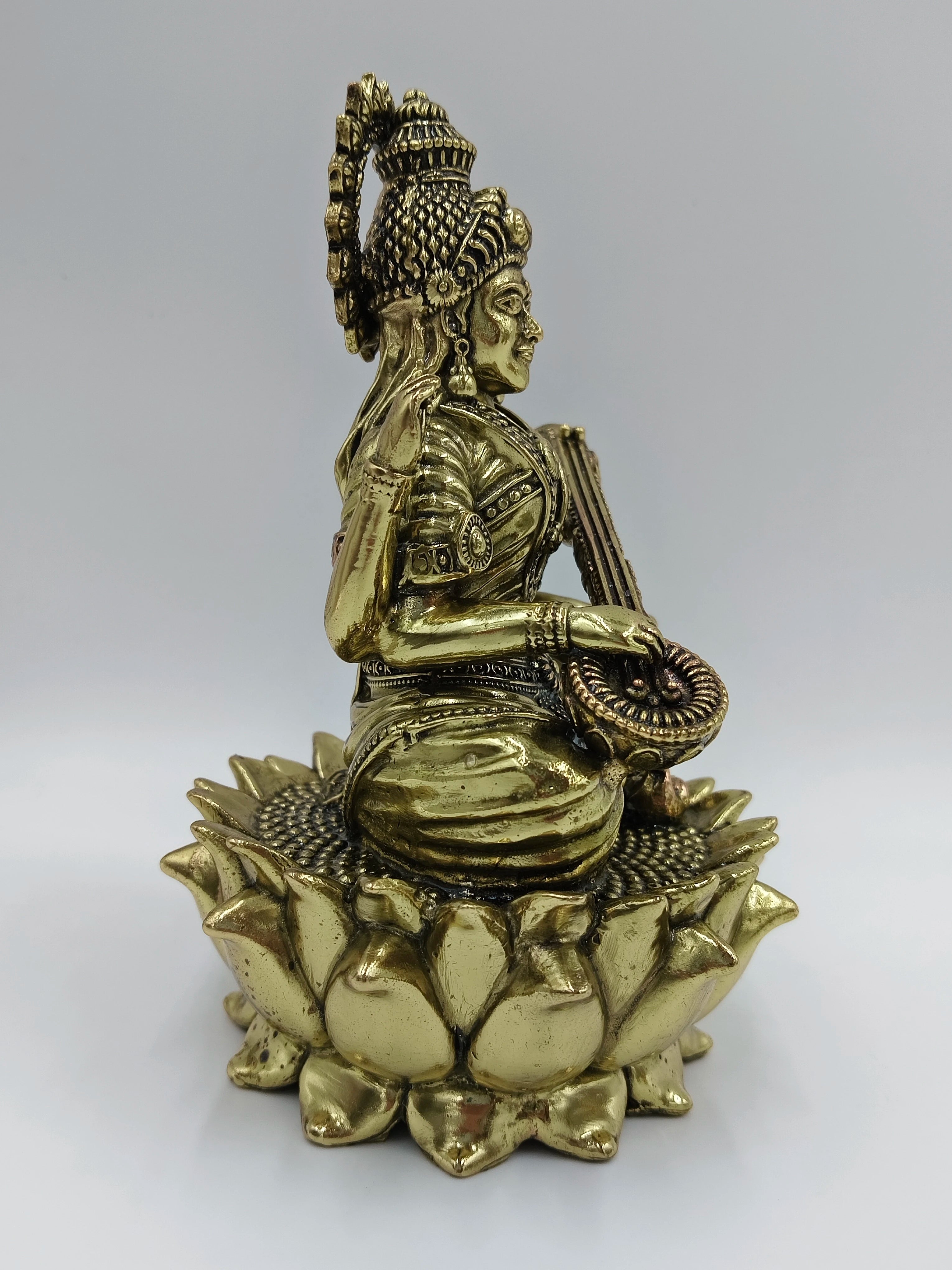 Side view of medium brass statue of Goddess Saraswathi sitting on a lotus
