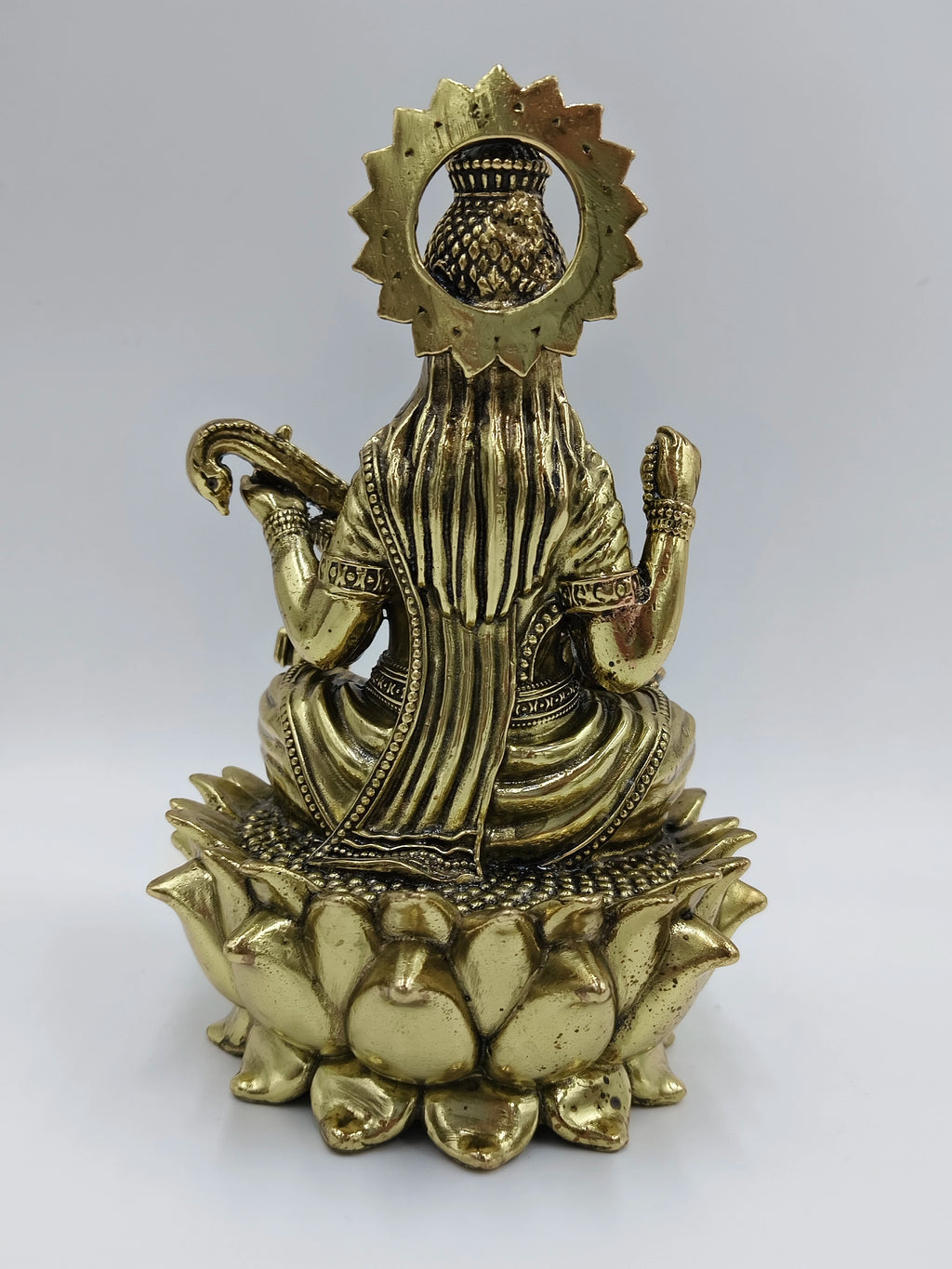 Back view of medium brass statue of Goddess Saraswathi sitting on a lotus