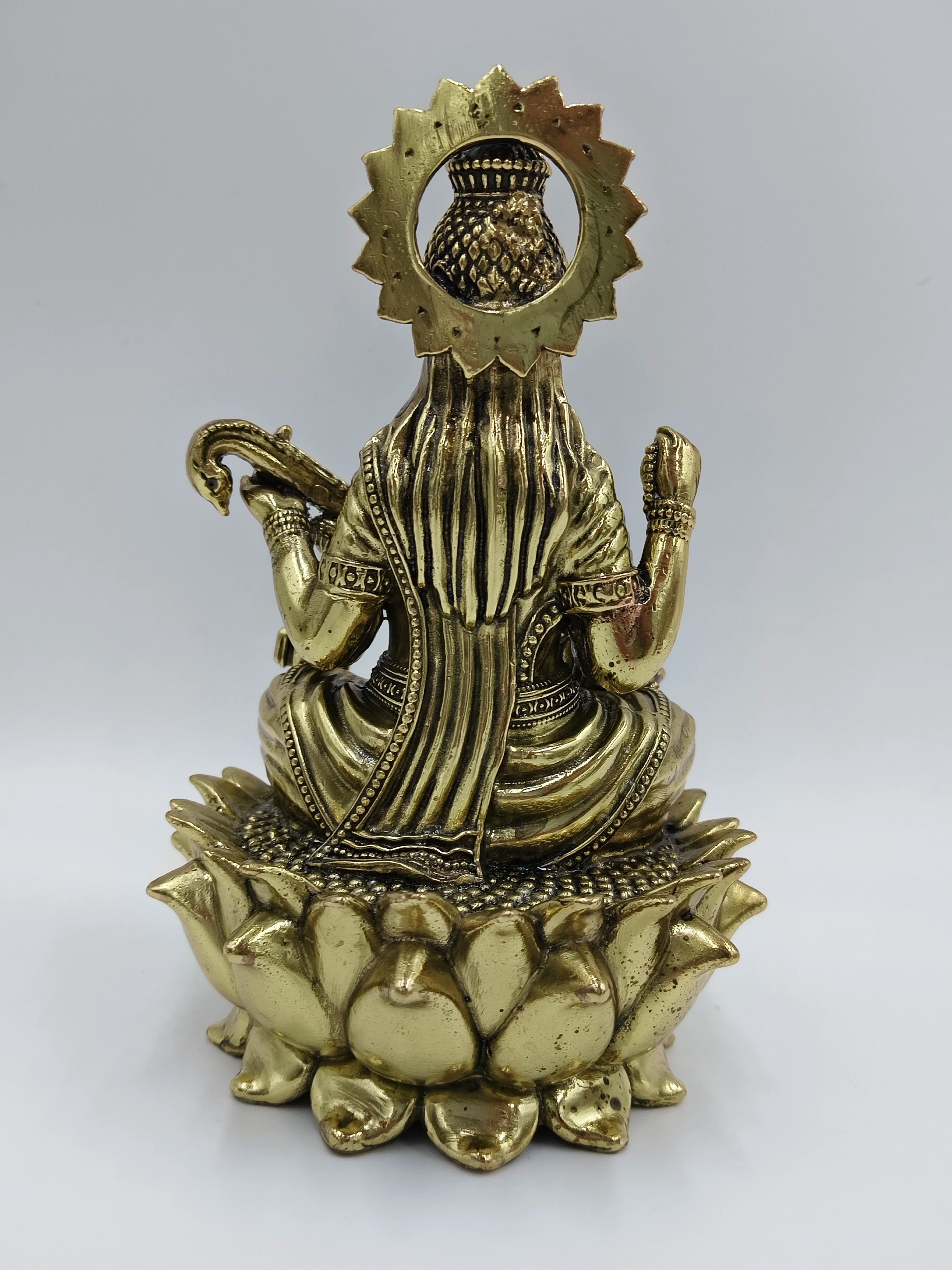 Back view of medium brass statue of Goddess Saraswathi sitting on a lotus