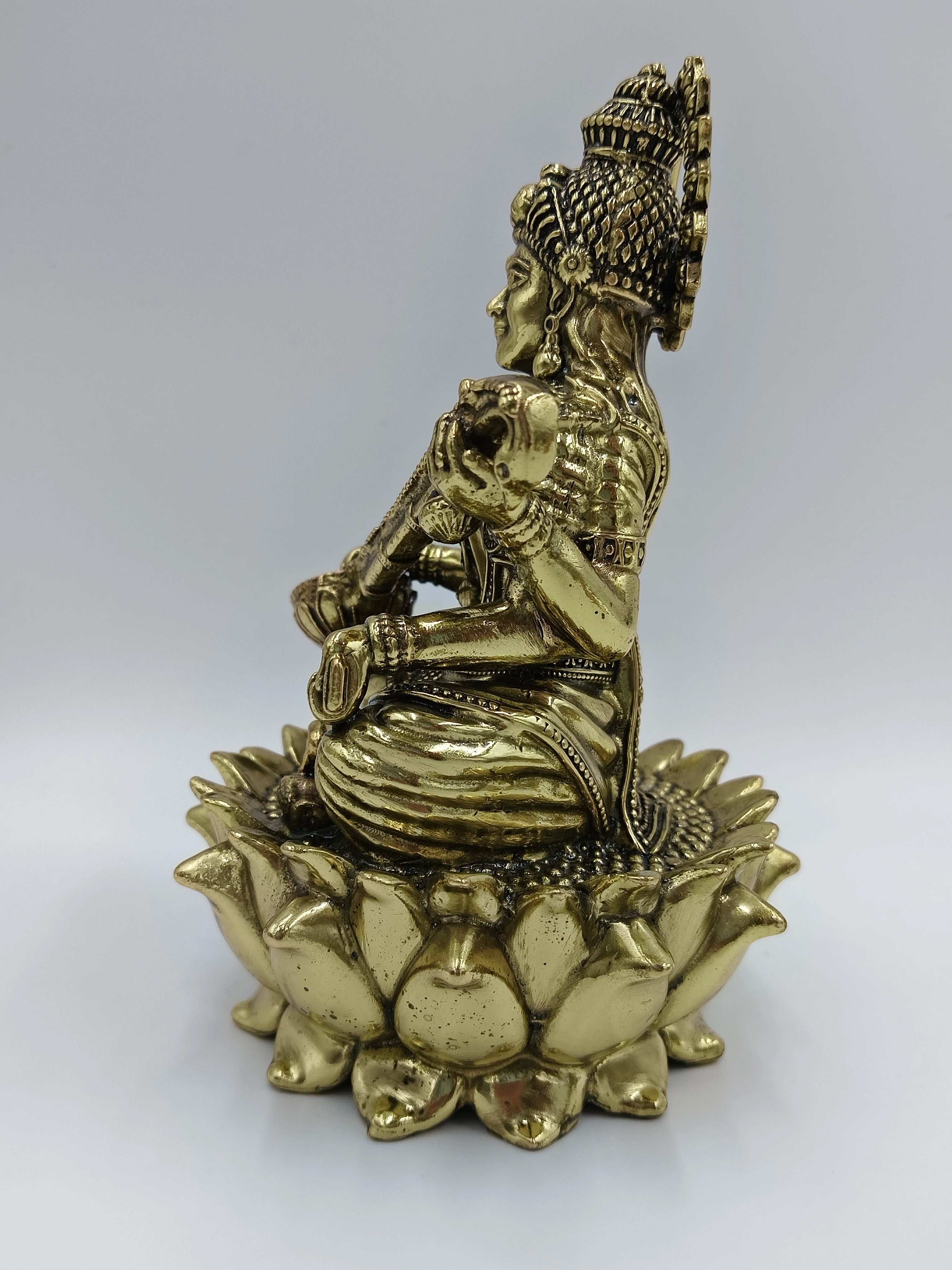 Side view of medium brass statue of Goddess Saraswathi seated on lotus