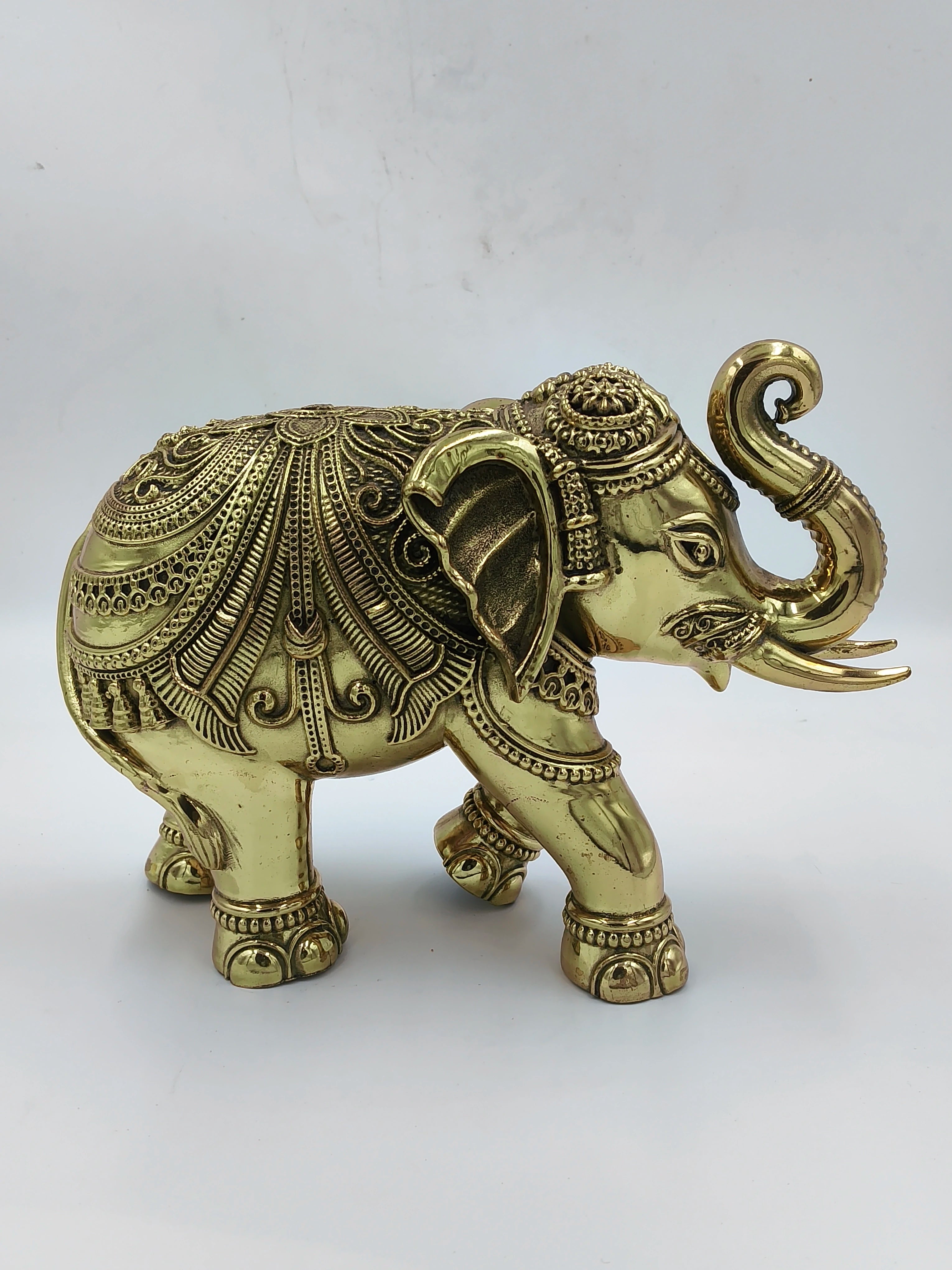 Large brass elephant figurine with intricate detailing and raised trunk side view
