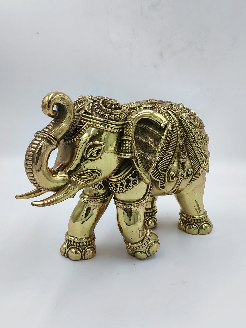 Large brass elephant sculpture with detailed ornamental carvings, side view