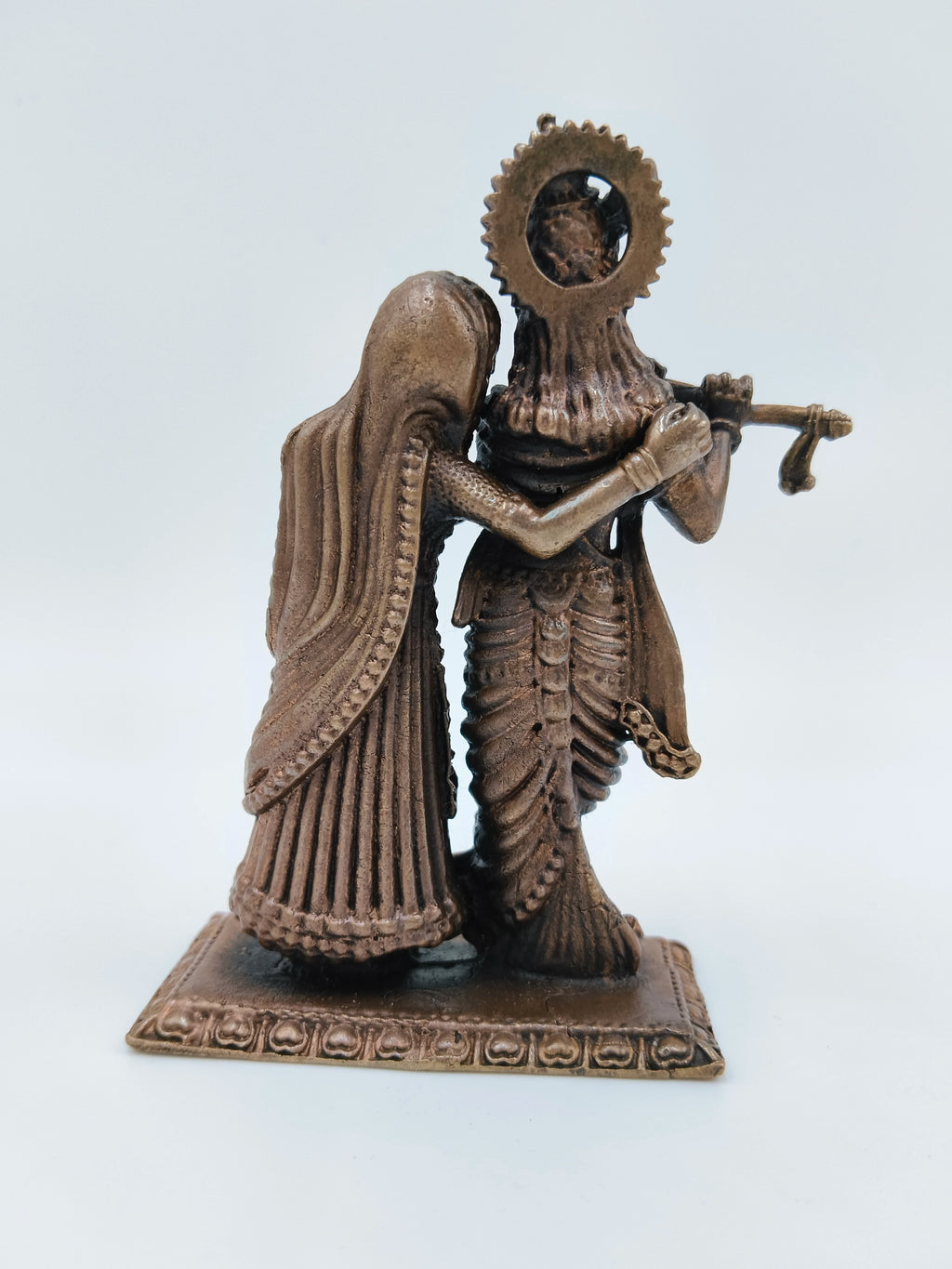 Back view of small copper Radha Krishna standing sculpture on a decorative base