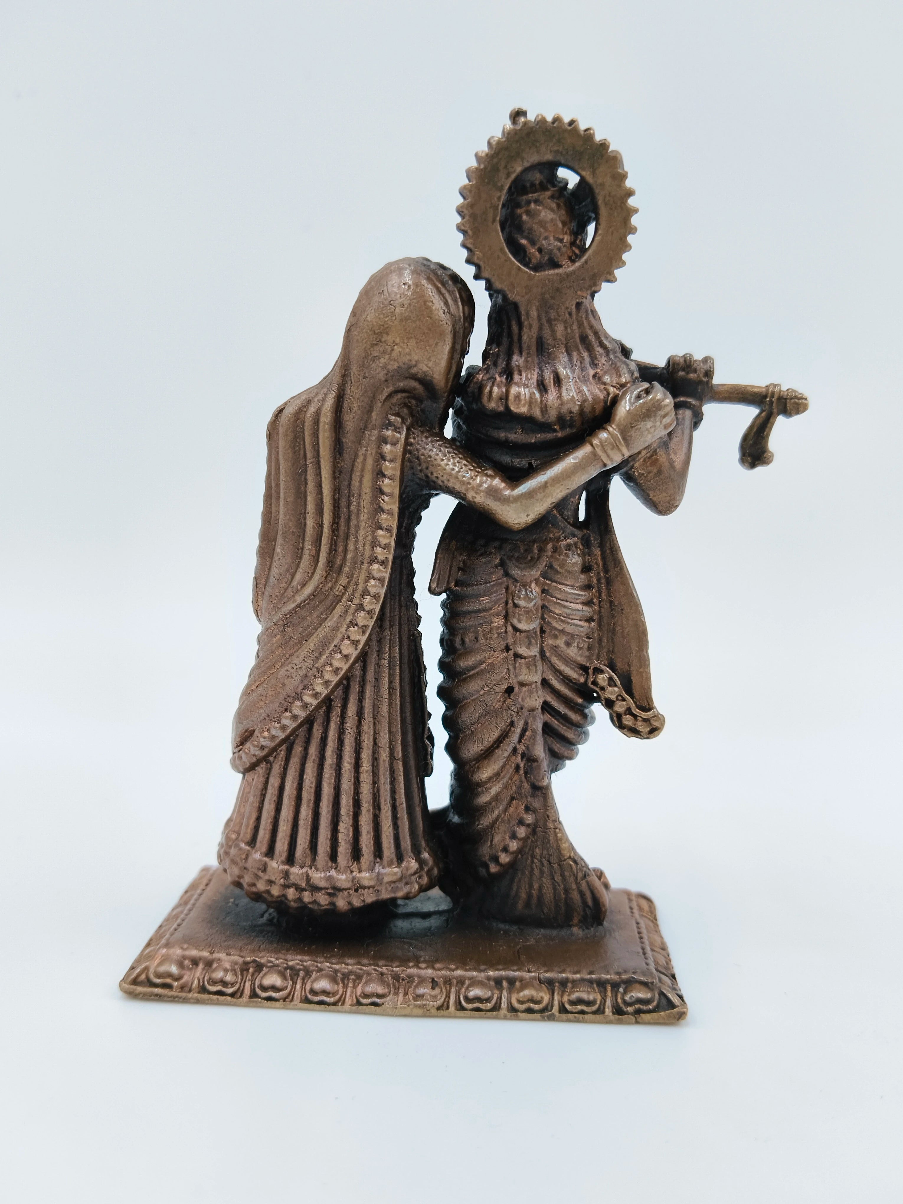 Back view of small copper Radha Krishna standing sculpture on a decorative base