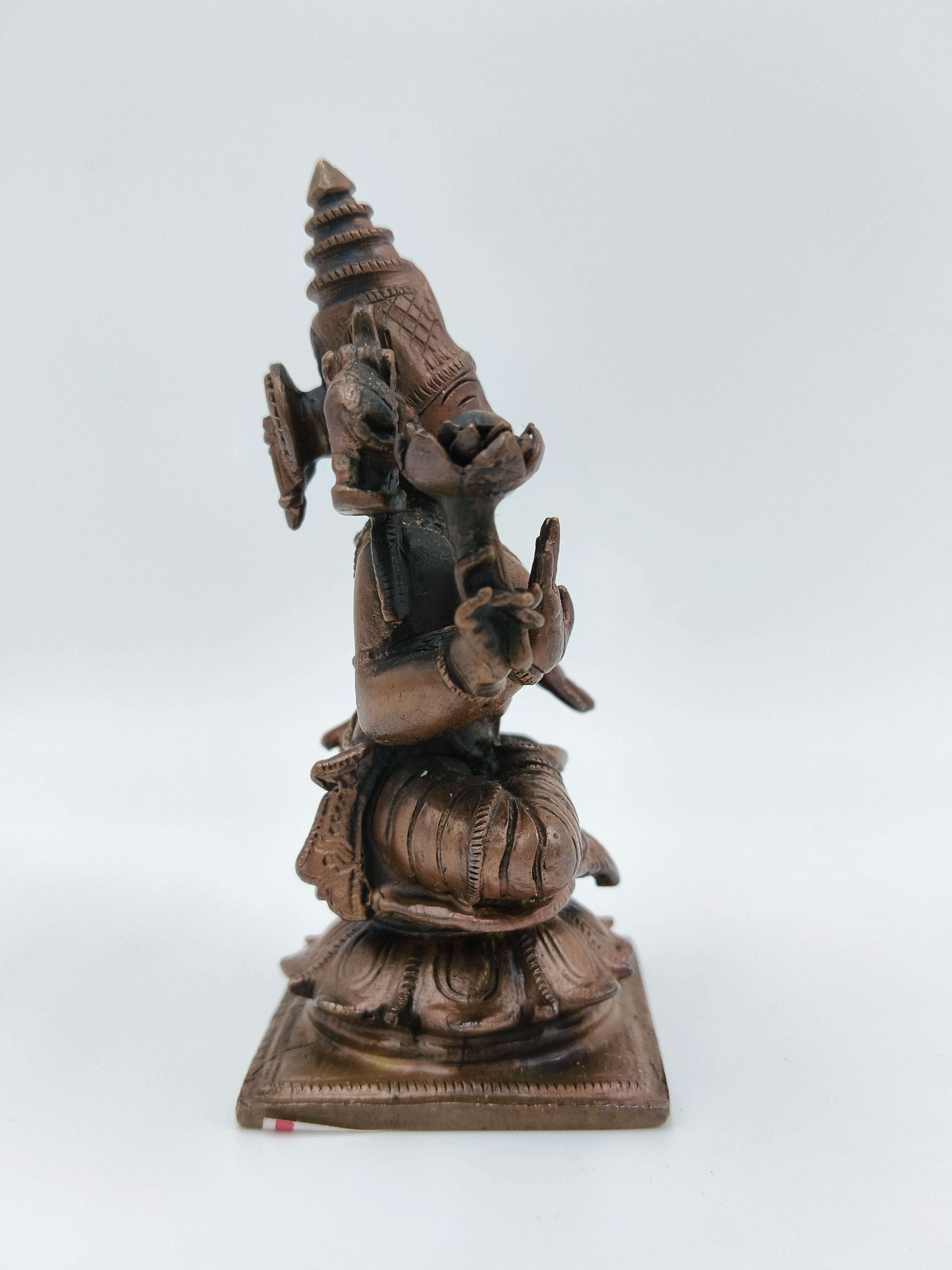 Side view of small brass Lakshmi sitting statue on square base