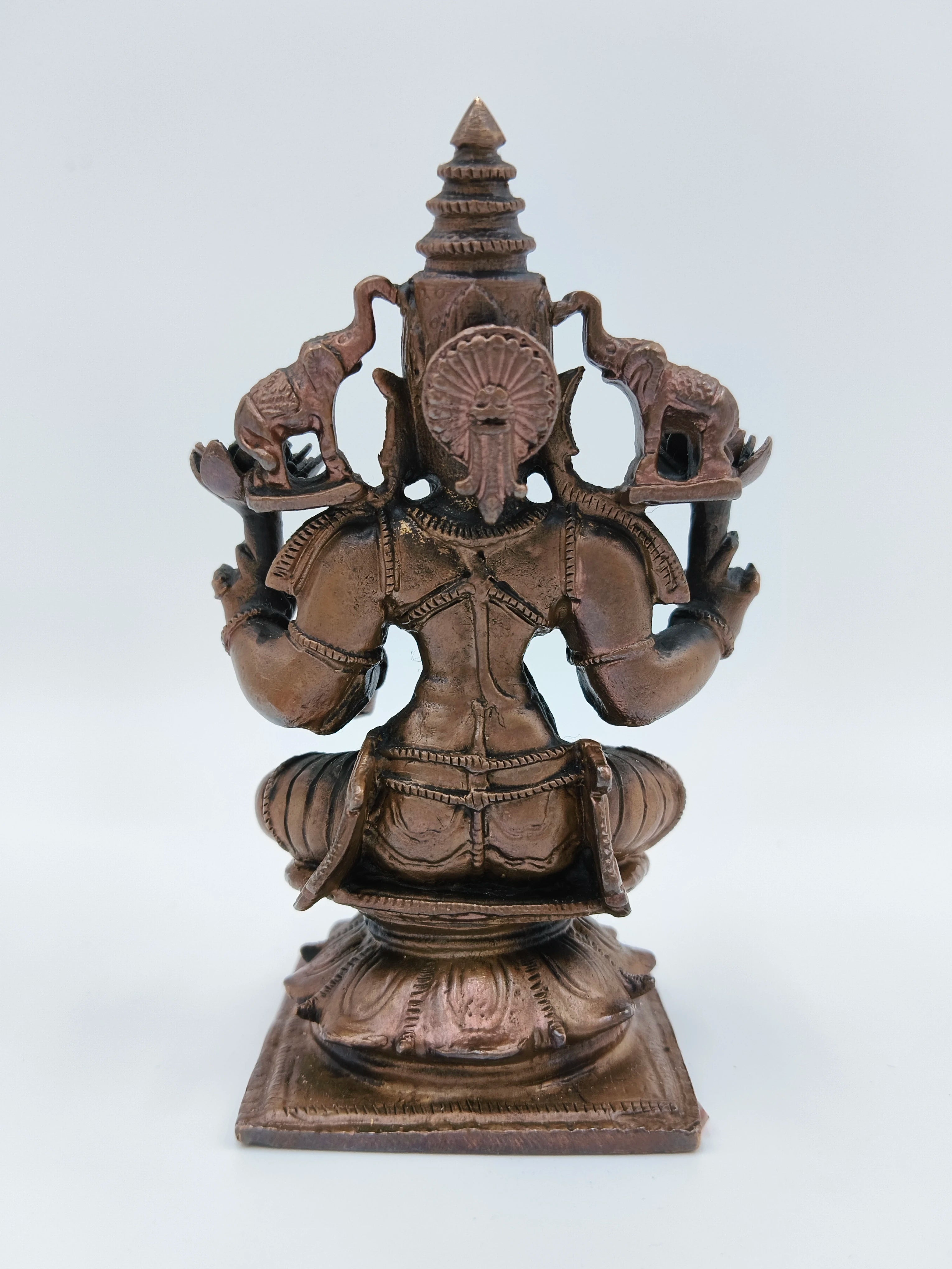 Back view of small seated Lakshmi brass sculpture with detailed carvings