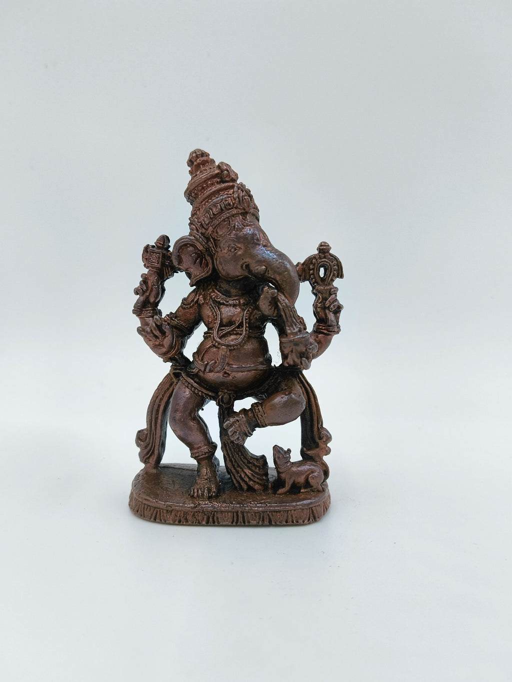 Small brass statue of Lord Ganesh in a joyful dancing pose on a tabletop