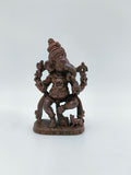 Small brass statue of Lord Ganesh in a joyful dancing pose on a tabletop