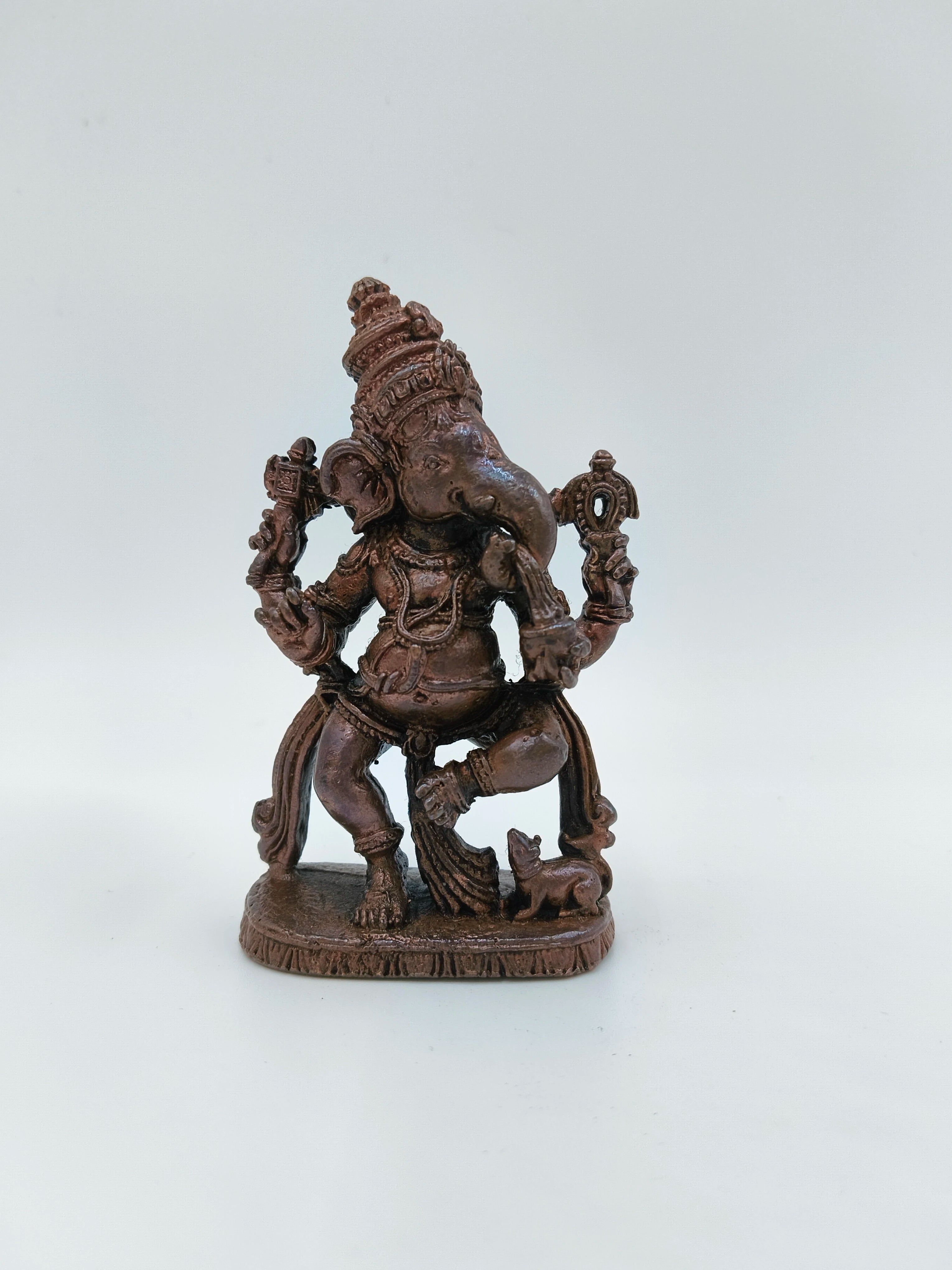 Small brass statue of Lord Ganesh in a joyful dancing pose on a tabletop