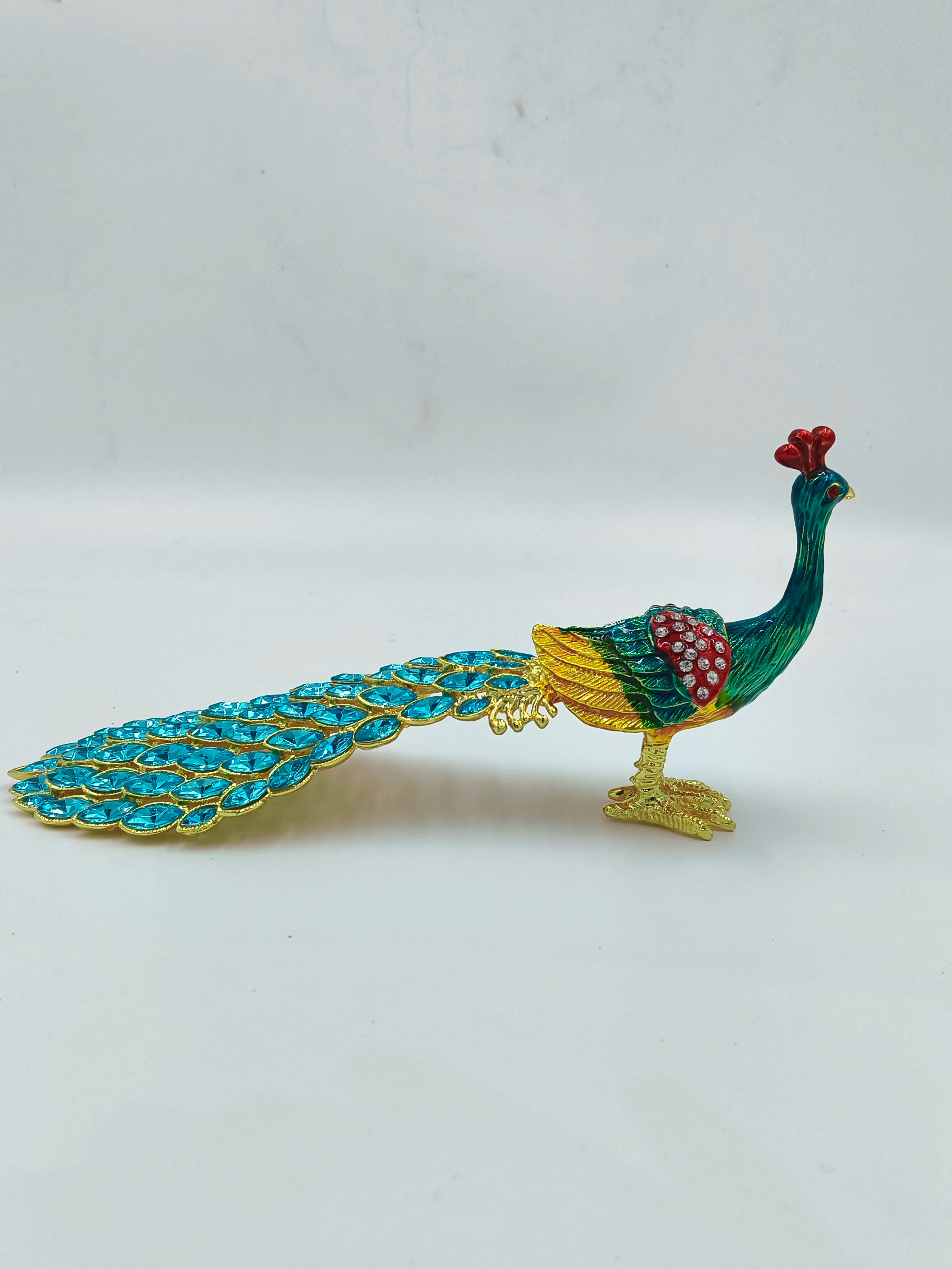 Small brass peacock figurine with copper enamel and blue tail stones side view