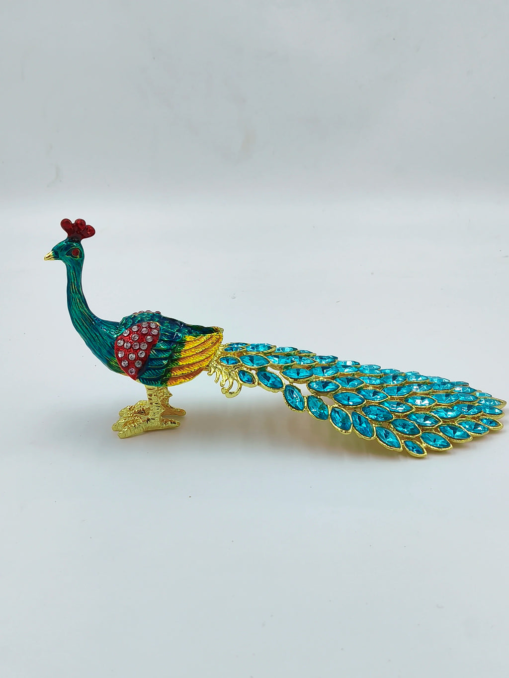 Small brass peacock figurine with copper enamel and blue gem tail detail