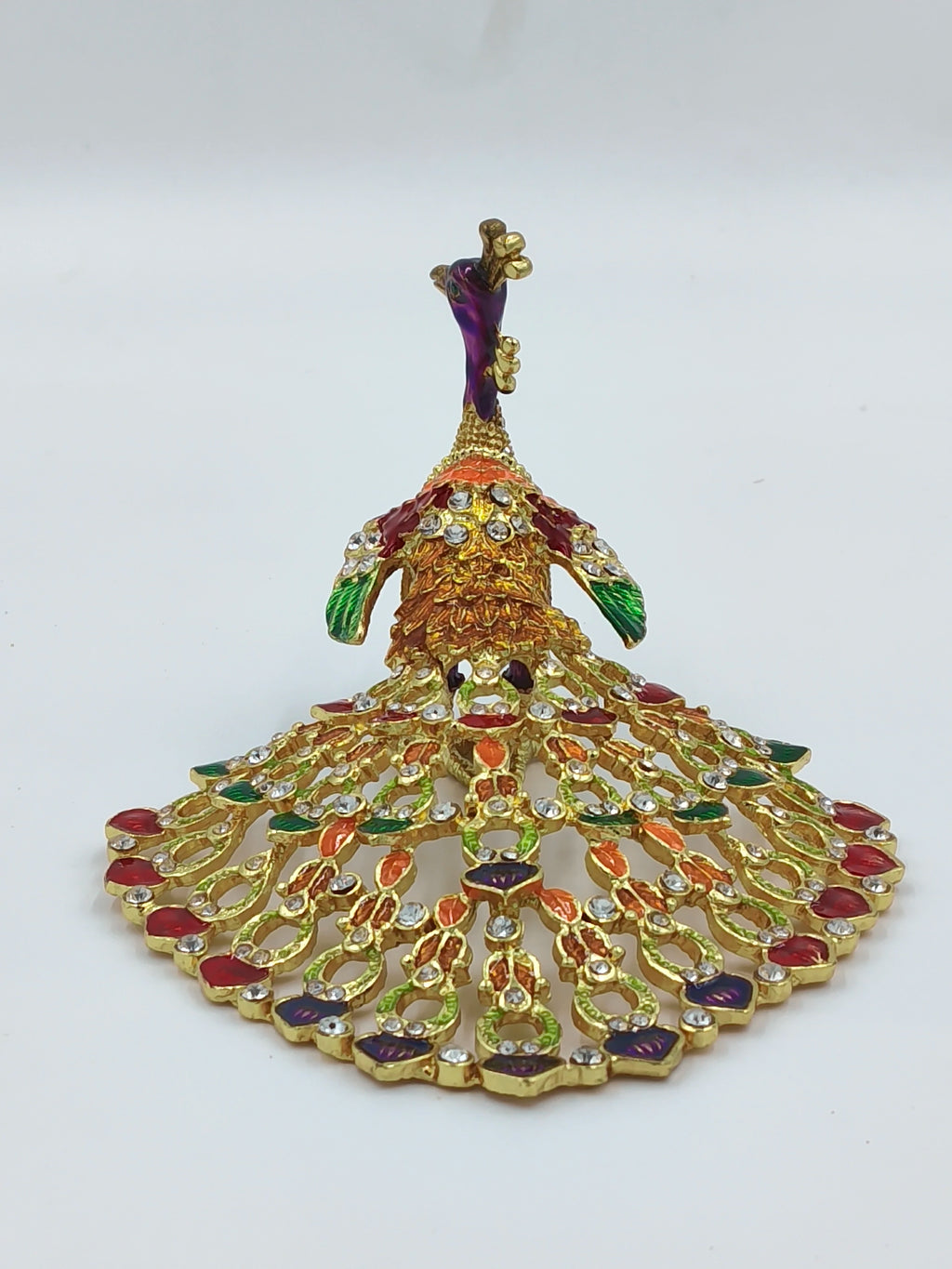 Small brass peacock figurine with copper enamel and gemstone details, front view