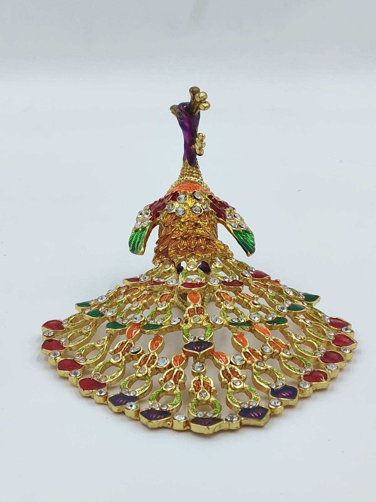 Small brass peacock figurine with copper enamel and gemstone details, front view
