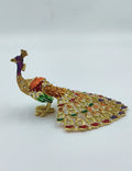 Small brass peacock figurine with copper enamel and jewel accents side view