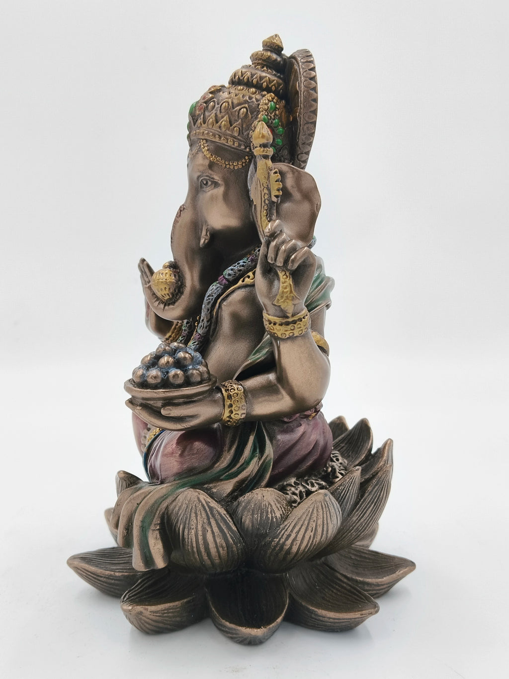 Side view of polyresin Ganesh sculpture seated on a lotus flower