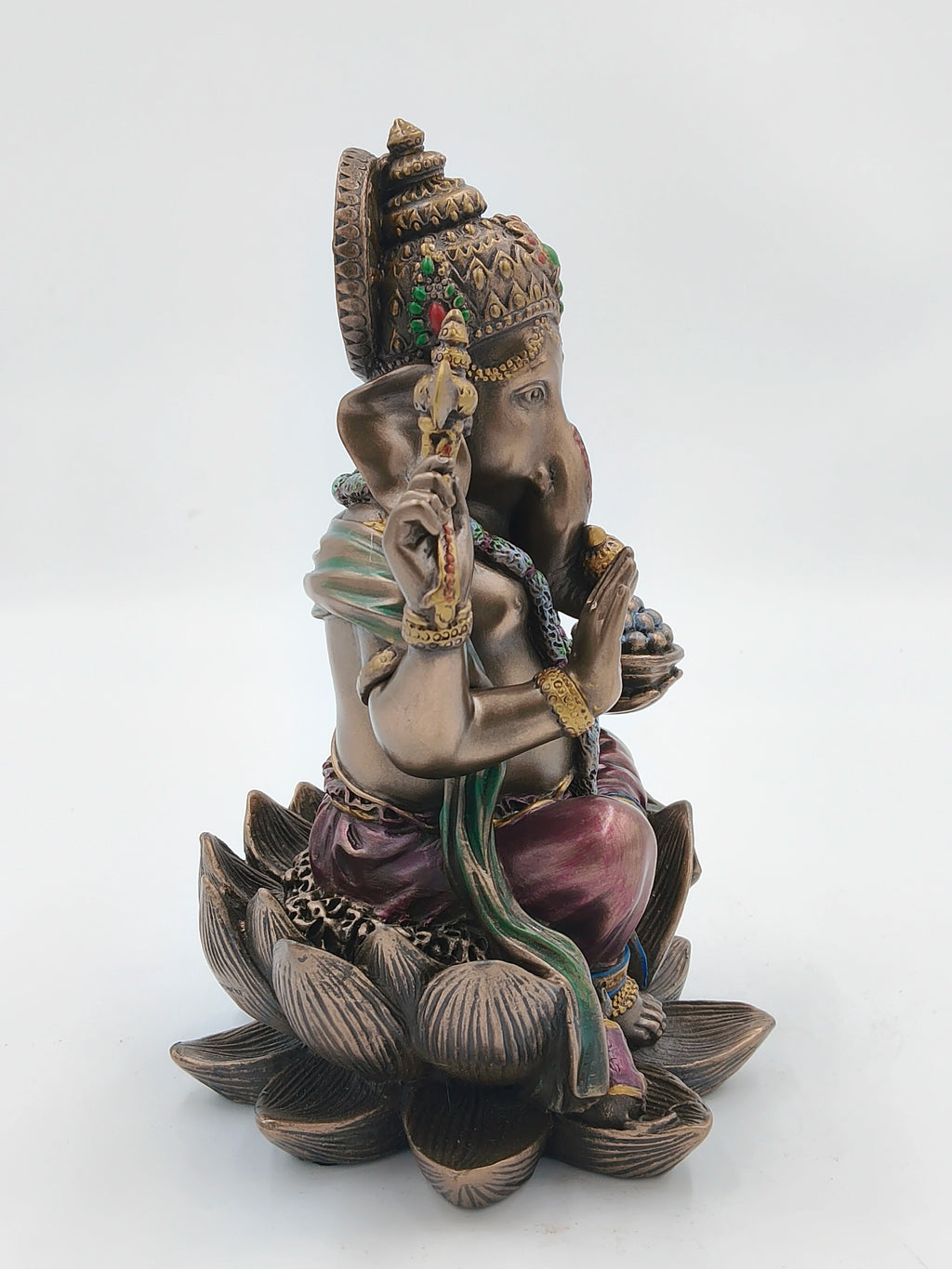 Polyresin Ganesh statue seated on a lotus with decorative attire and ornaments side view