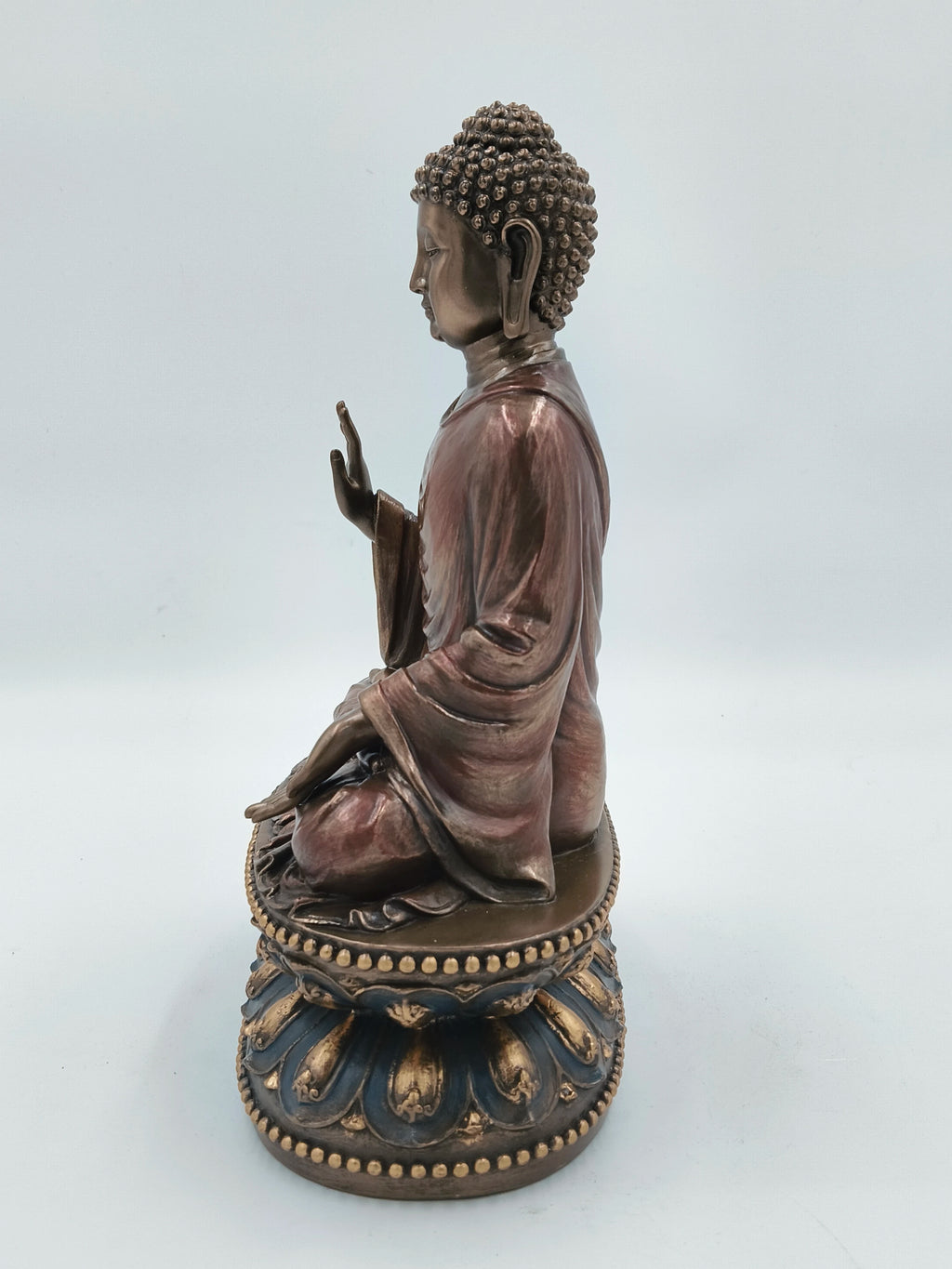 Side view of large polyresin Buddha sculpture seated on decorated pedestal