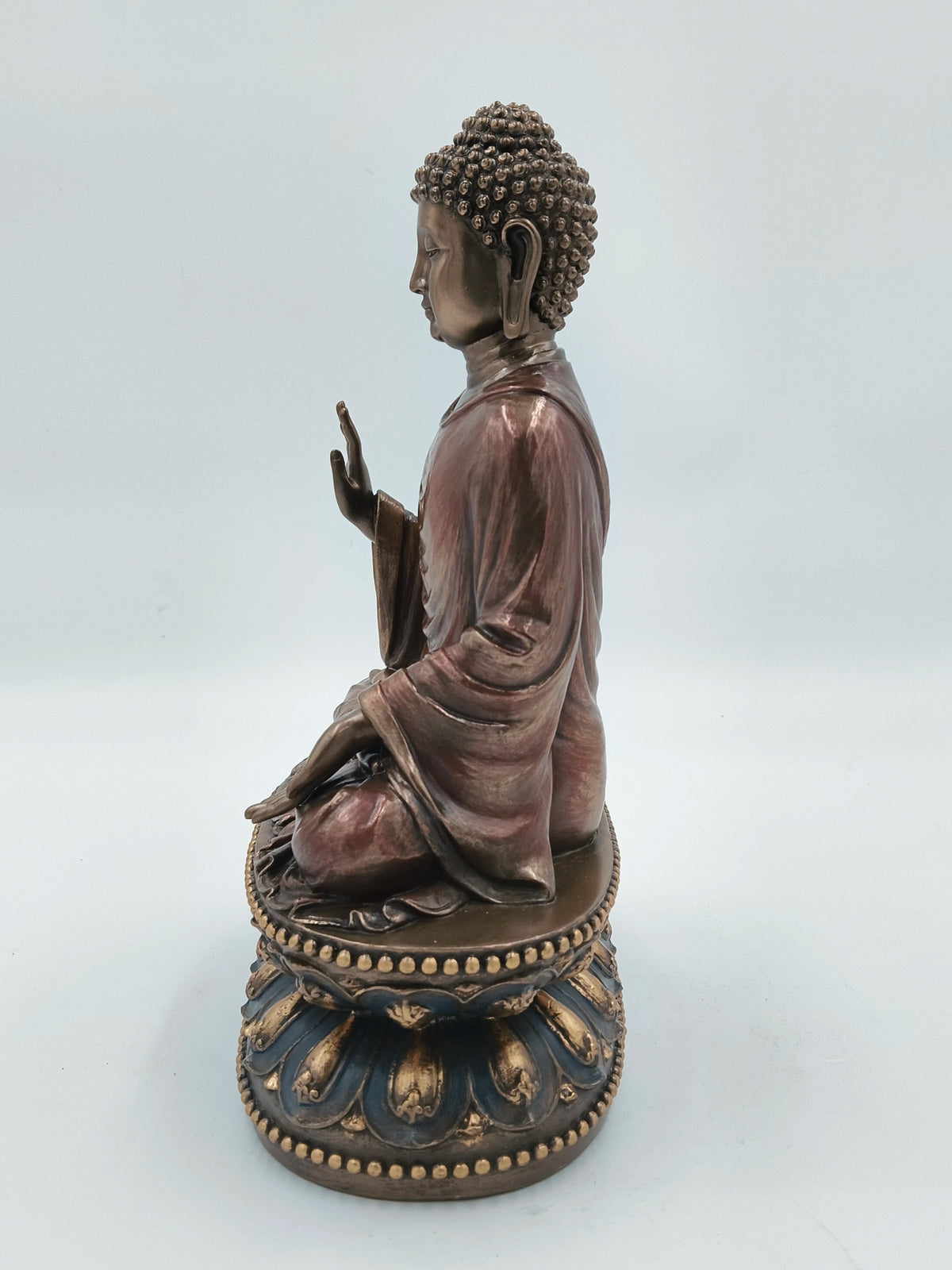 Side view of large polyresin Buddha sculpture seated on decorated pedestal