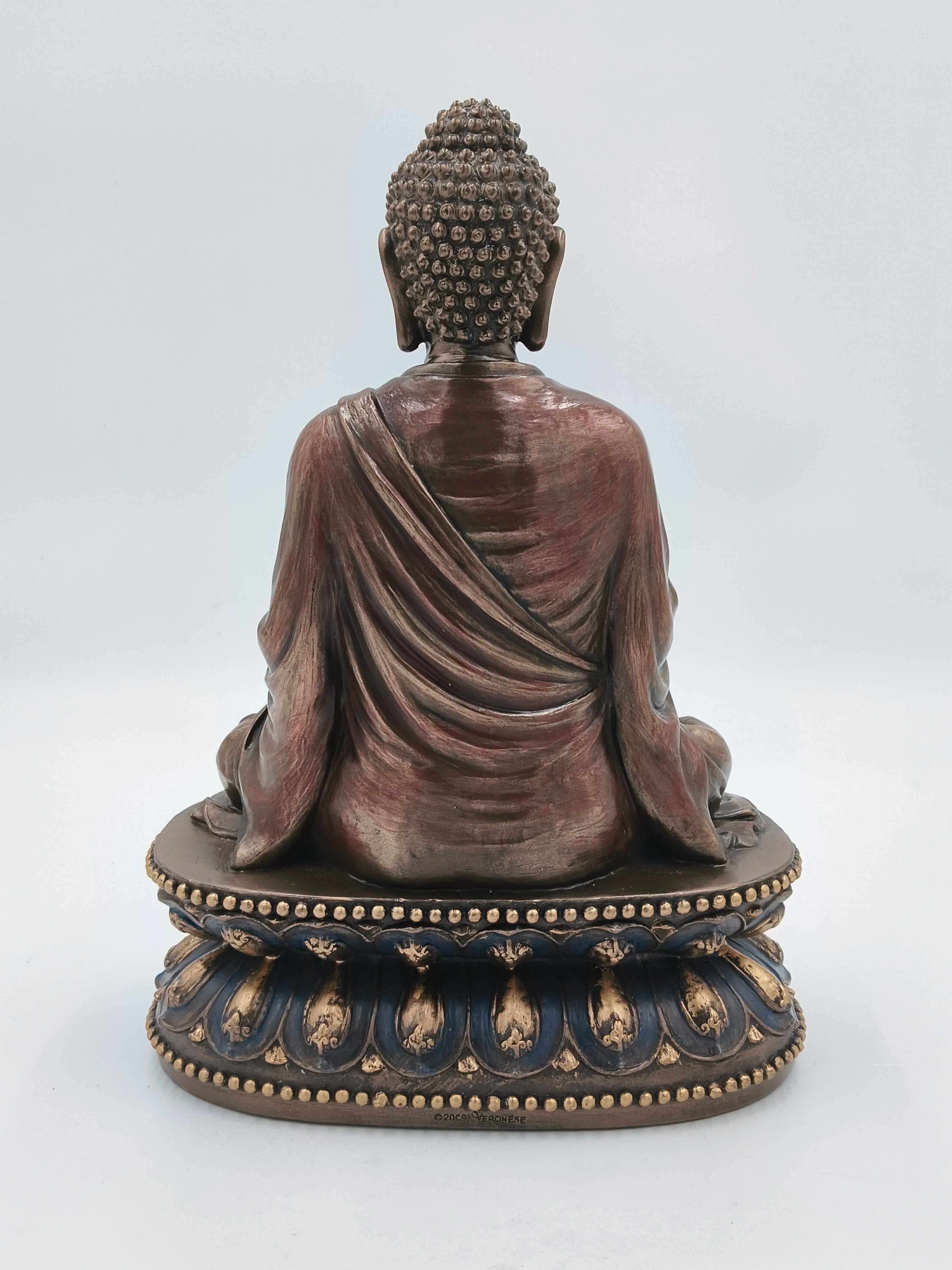Back view of a large polyresin Buddha statue seated on an ornate base