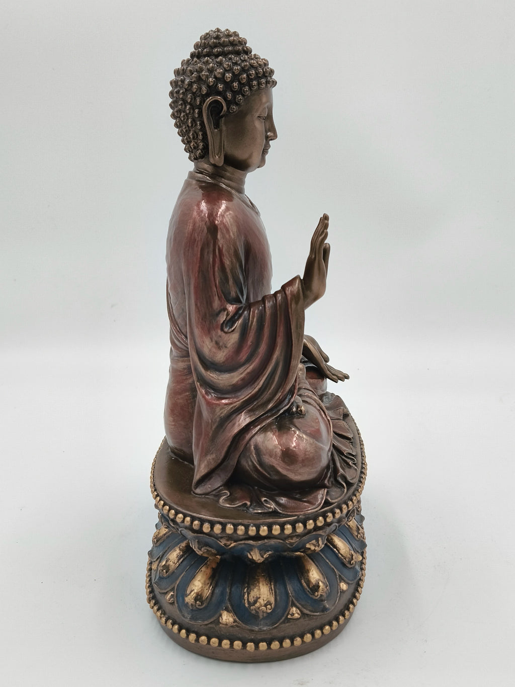 Side view of a large polyresin Buddha statue seated on an ornate lotus pedestal
