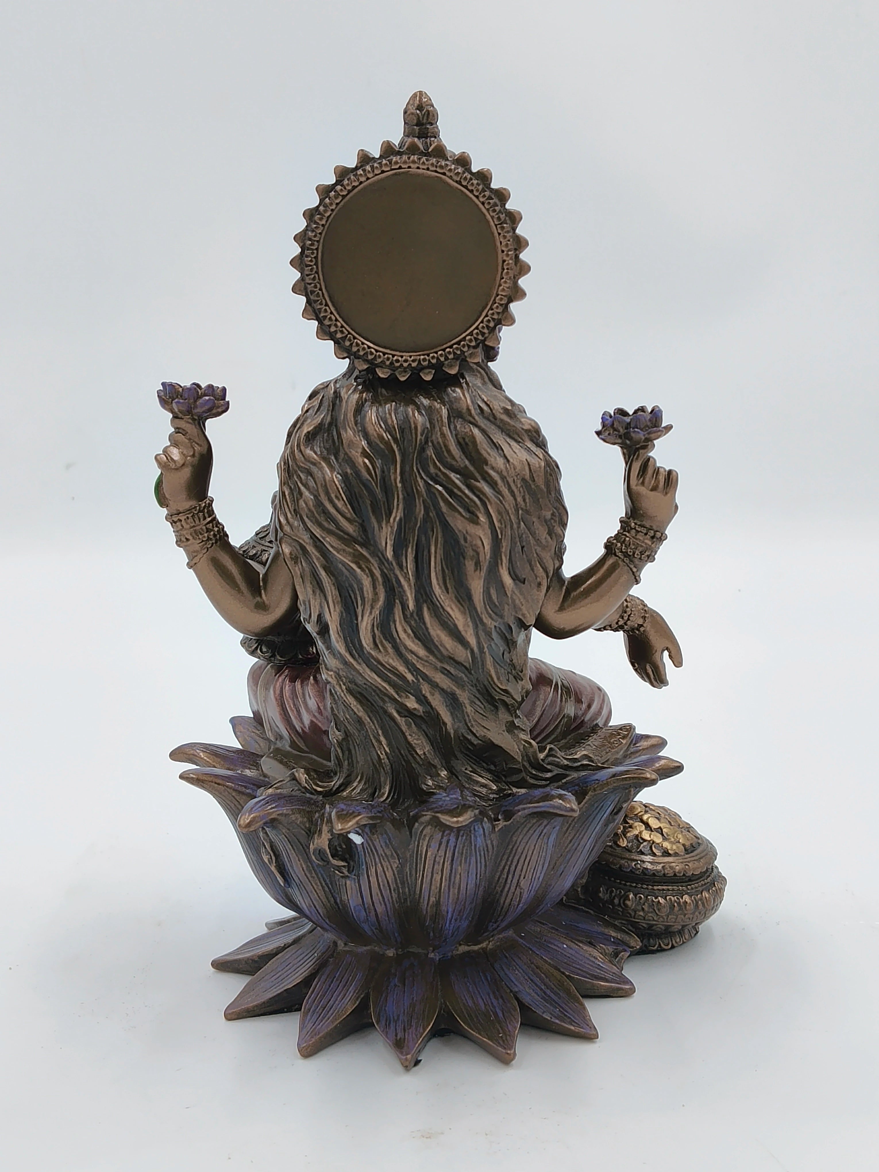 Back view of large polyresin Lakshmi sculpture seated on lotus pedestal with flowers