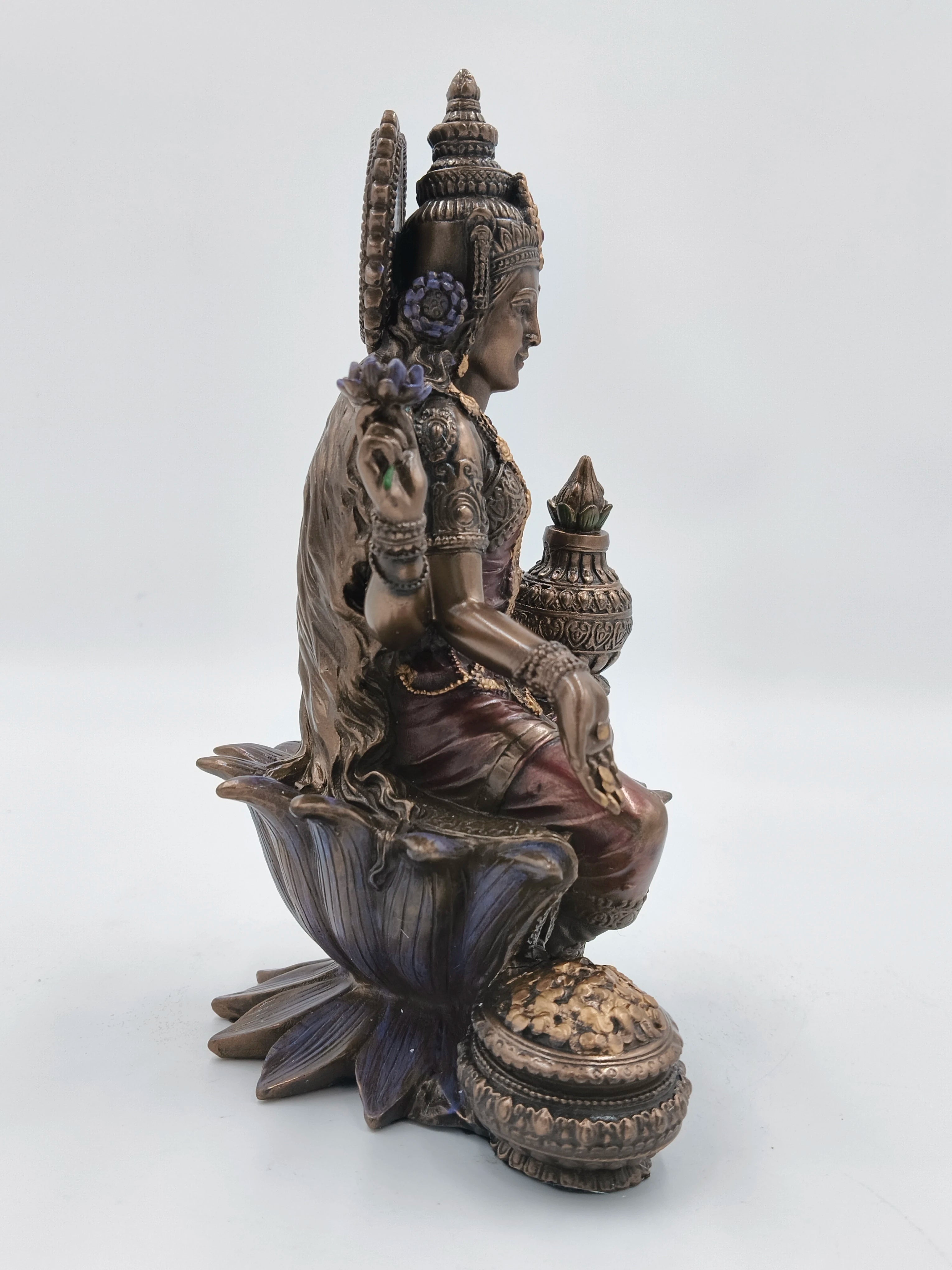 Side view of polyresin Lakshmi statue seated on lotus with detailed adornments