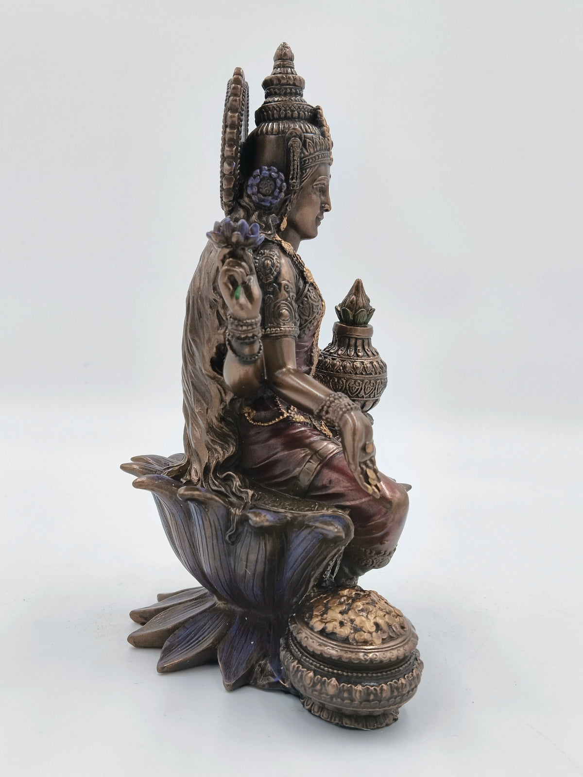 Side view of polyresin Lakshmi statue seated on lotus with detailed adornments