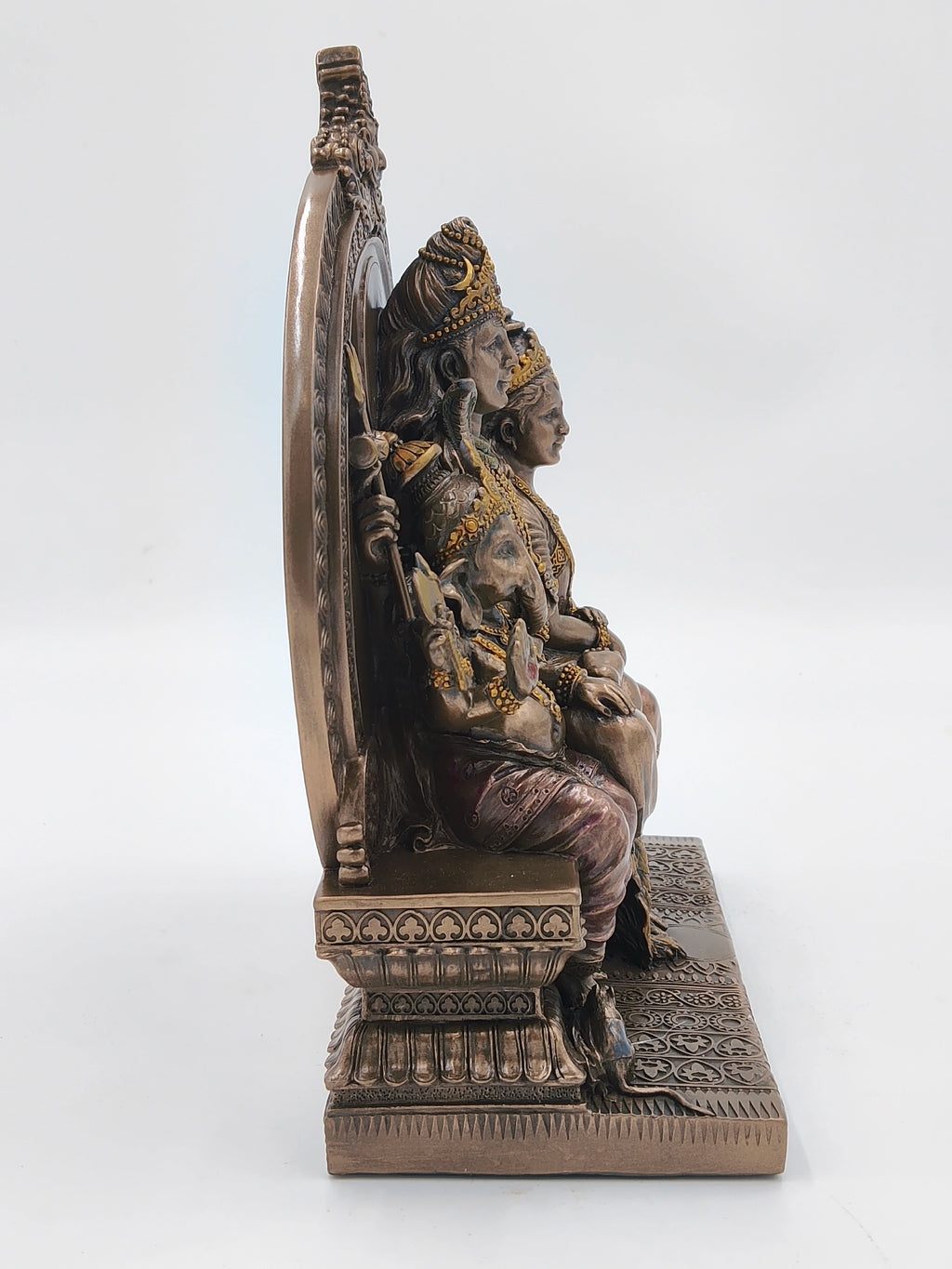 Side view of polyresin sculpture of Shiva family seated on decorated sinhasan