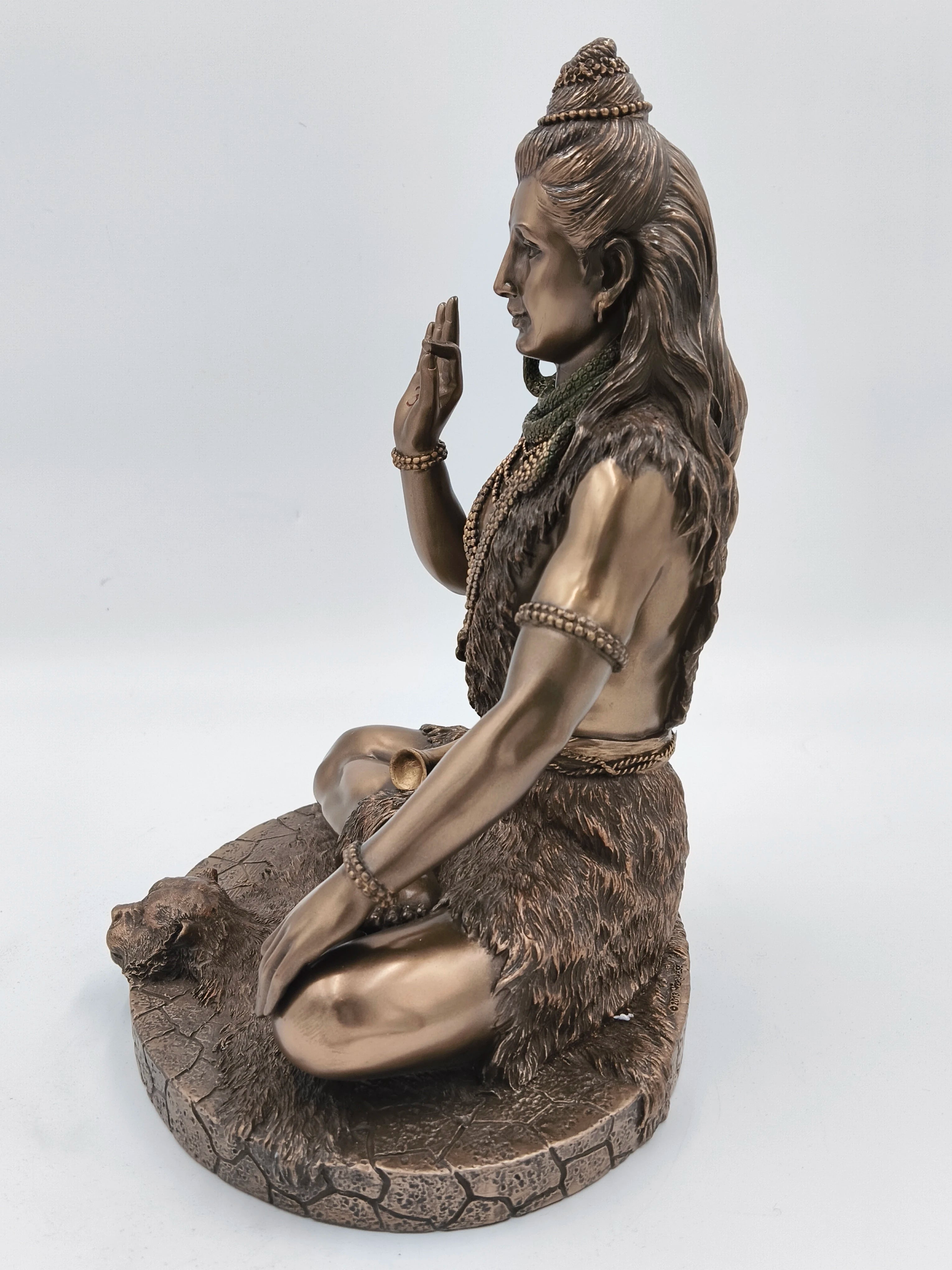 Side view of large polyresin statue of Shiva sitting with raised right hand