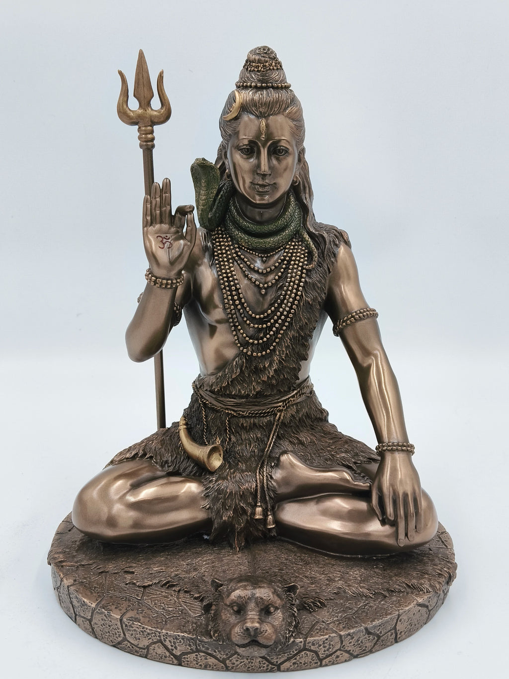Polyresin sculpture of Shiva seated cross-legged, holding trident and showing blessing gesture