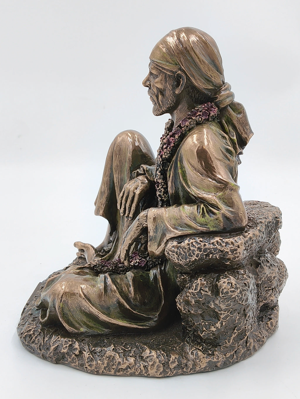 Side view of large polyresin Shirdi Sai Baba statue seated on rock base