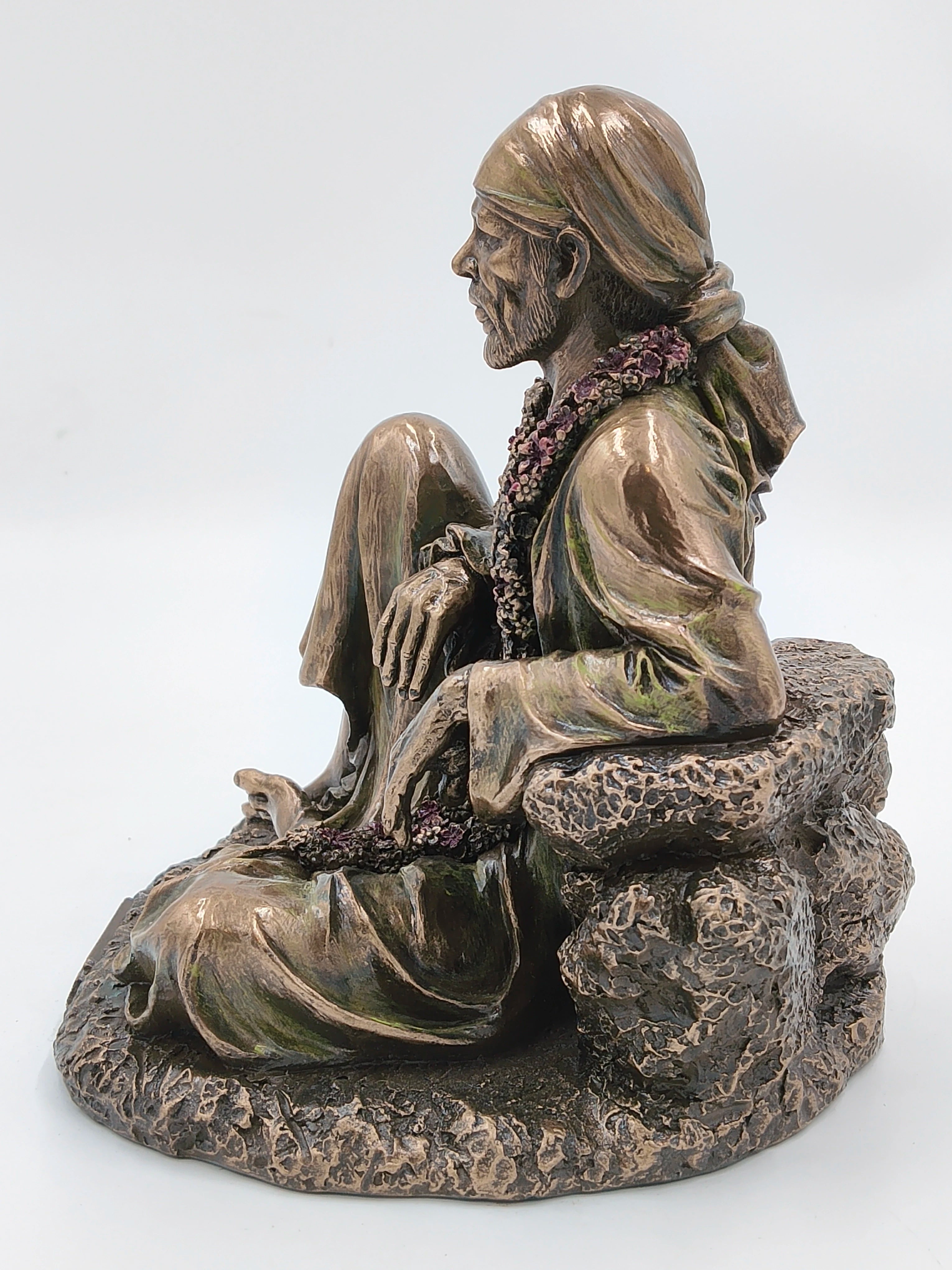 Side view of large polyresin Shirdi Sai Baba statue seated on rock base