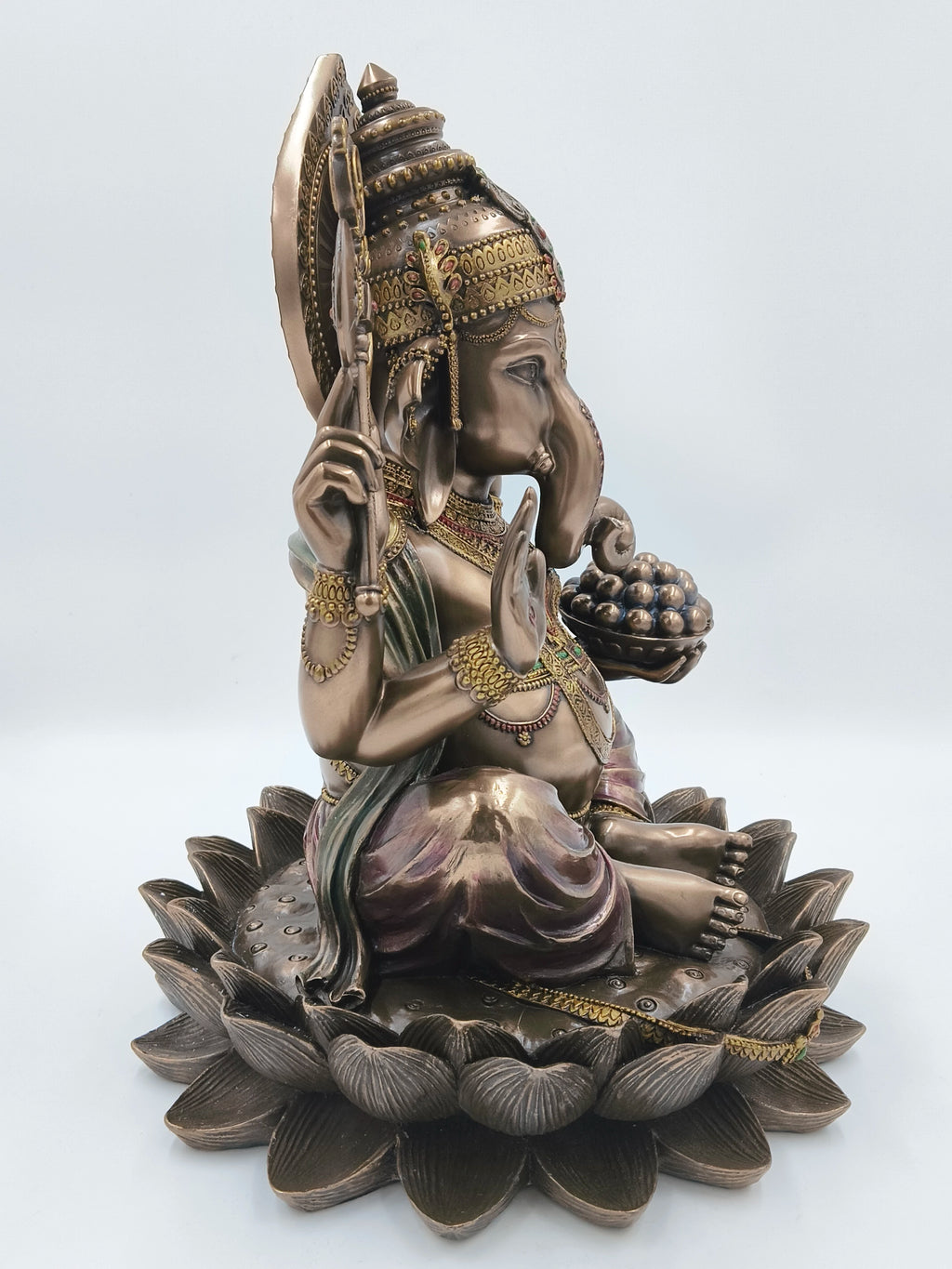 side view of large polyresin Ganesh statue seated on lotus base with detailed ornamentation