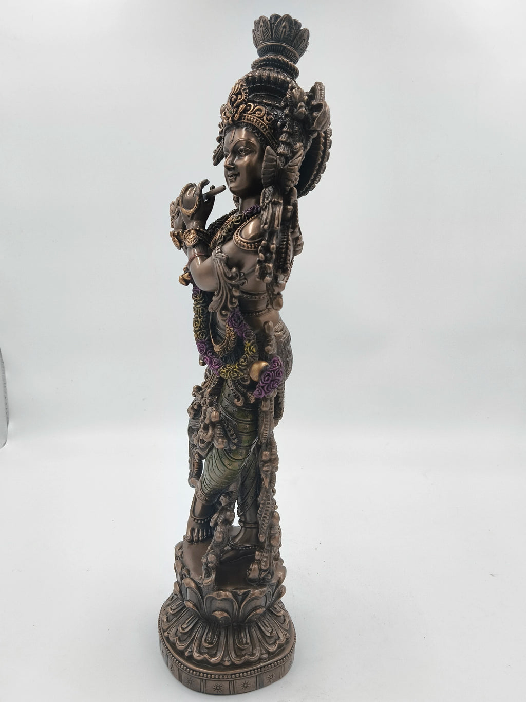 Side view of a large polyresin Krishna statue playing a flute with detailed ornamentation
