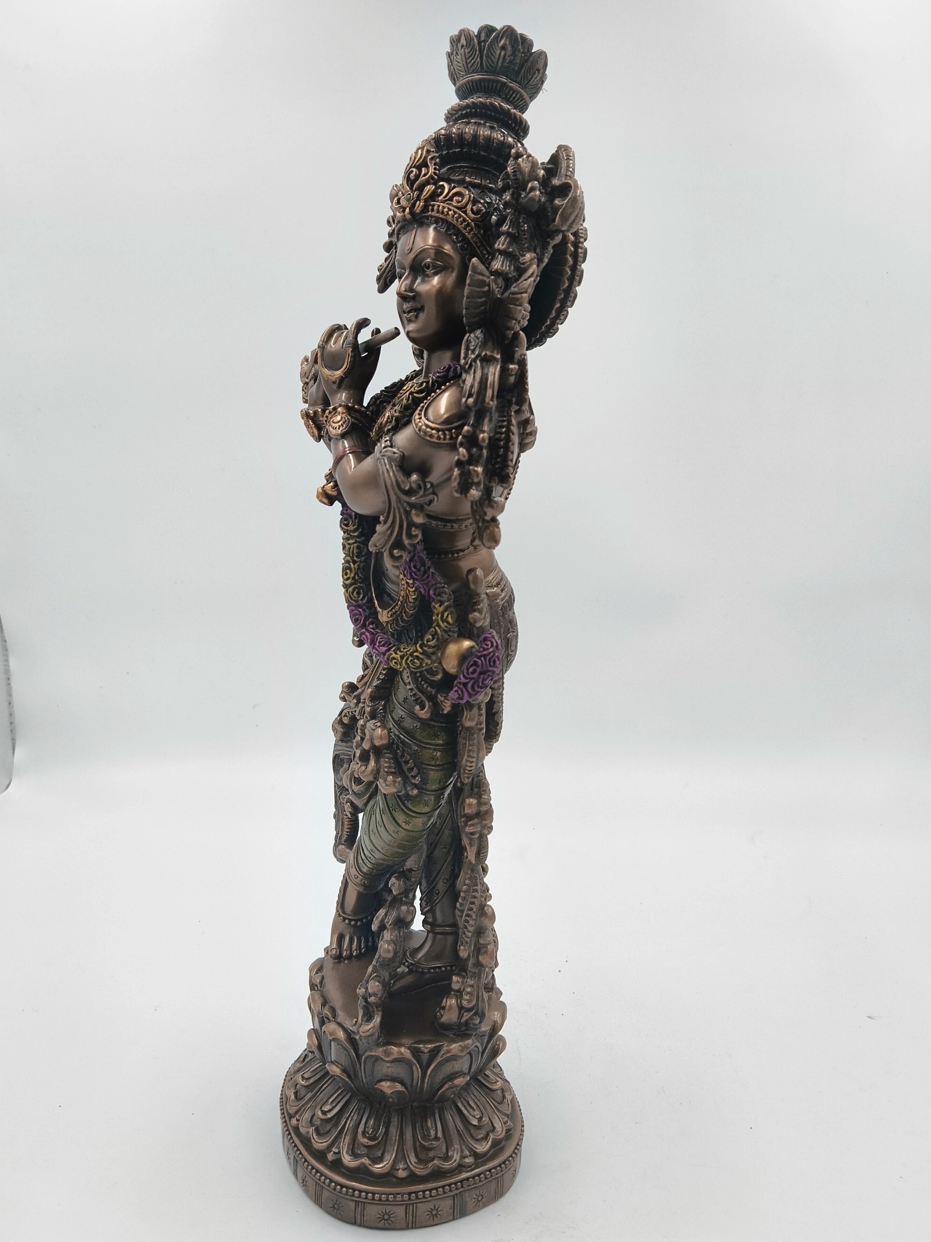 Side view of a large polyresin Krishna statue playing a flute with detailed ornamentation
