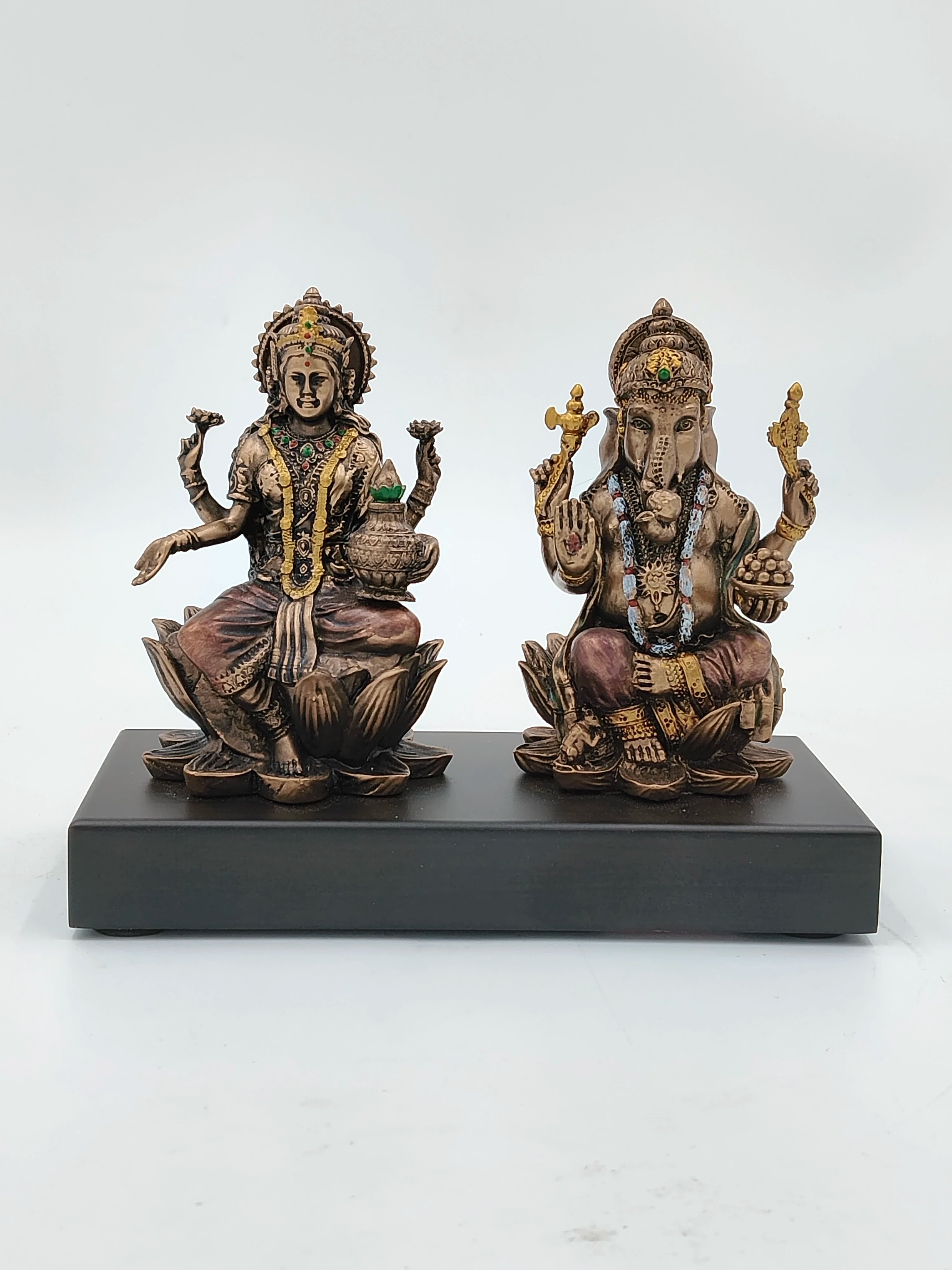 small polyresin Ganesh and Lakshmi statues seated on lotus on black base