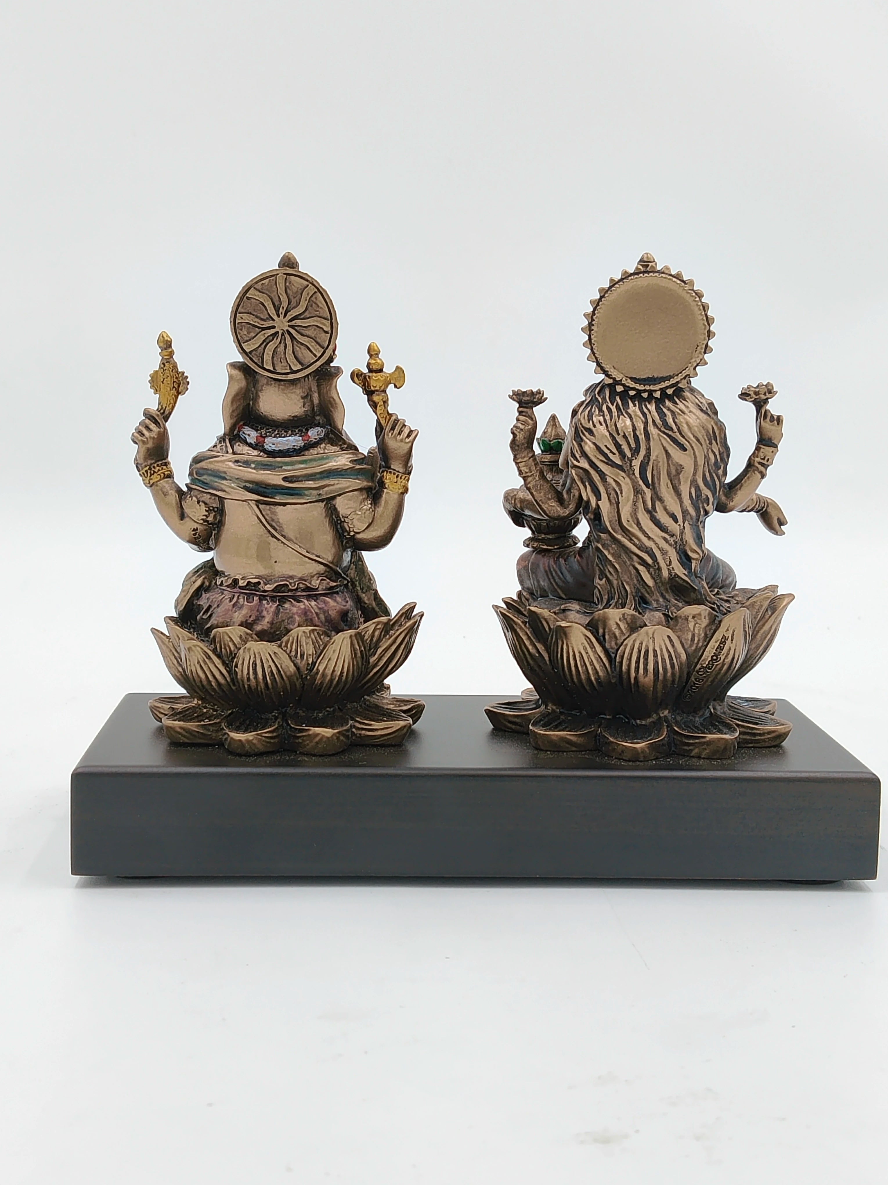 Back view of small polyresin Ganesh and Lakshmi statues seated on lotus base on black platform