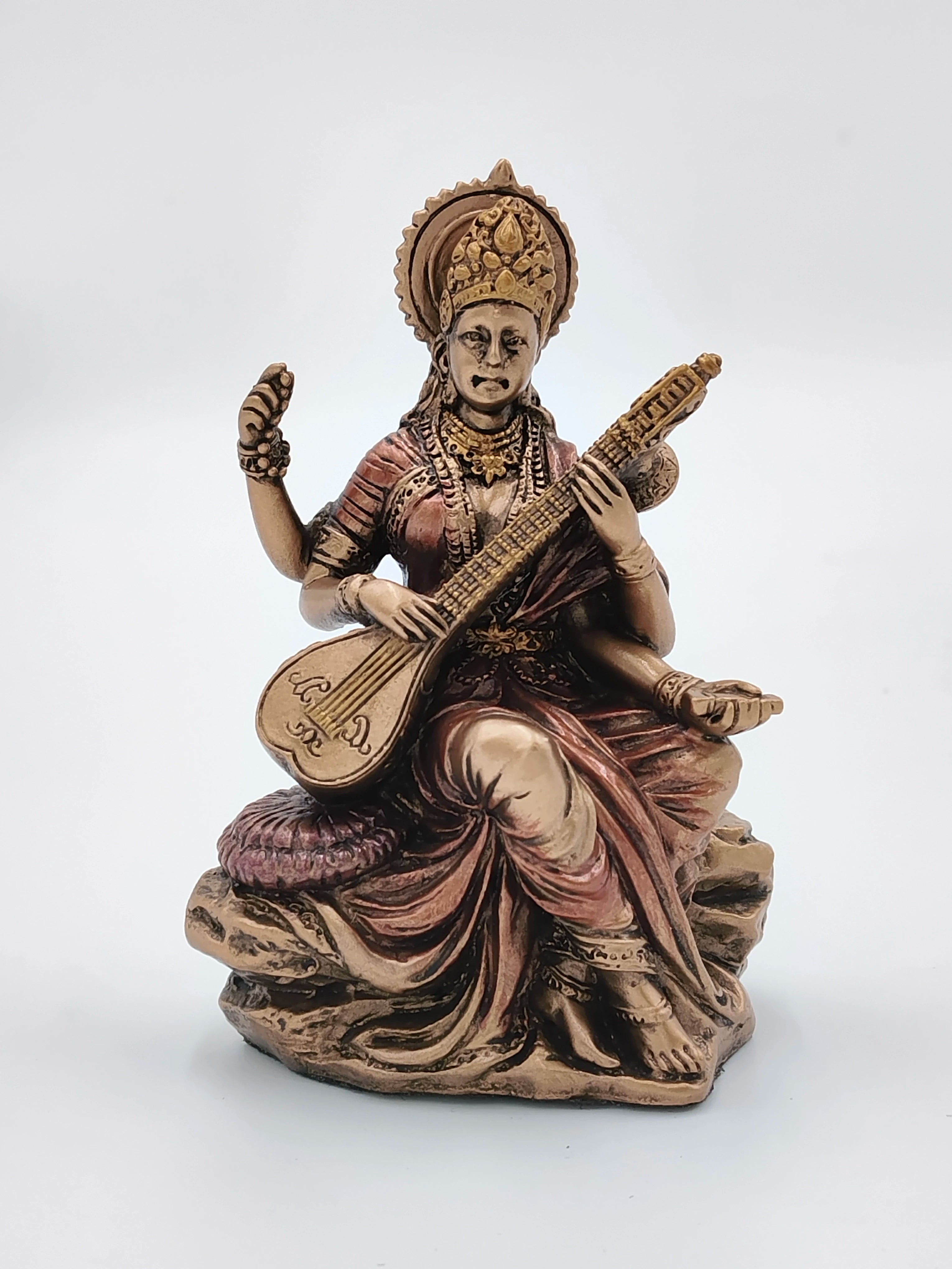 Small polyresin statue of goddess Saraswathi playing veena, seated on a rock